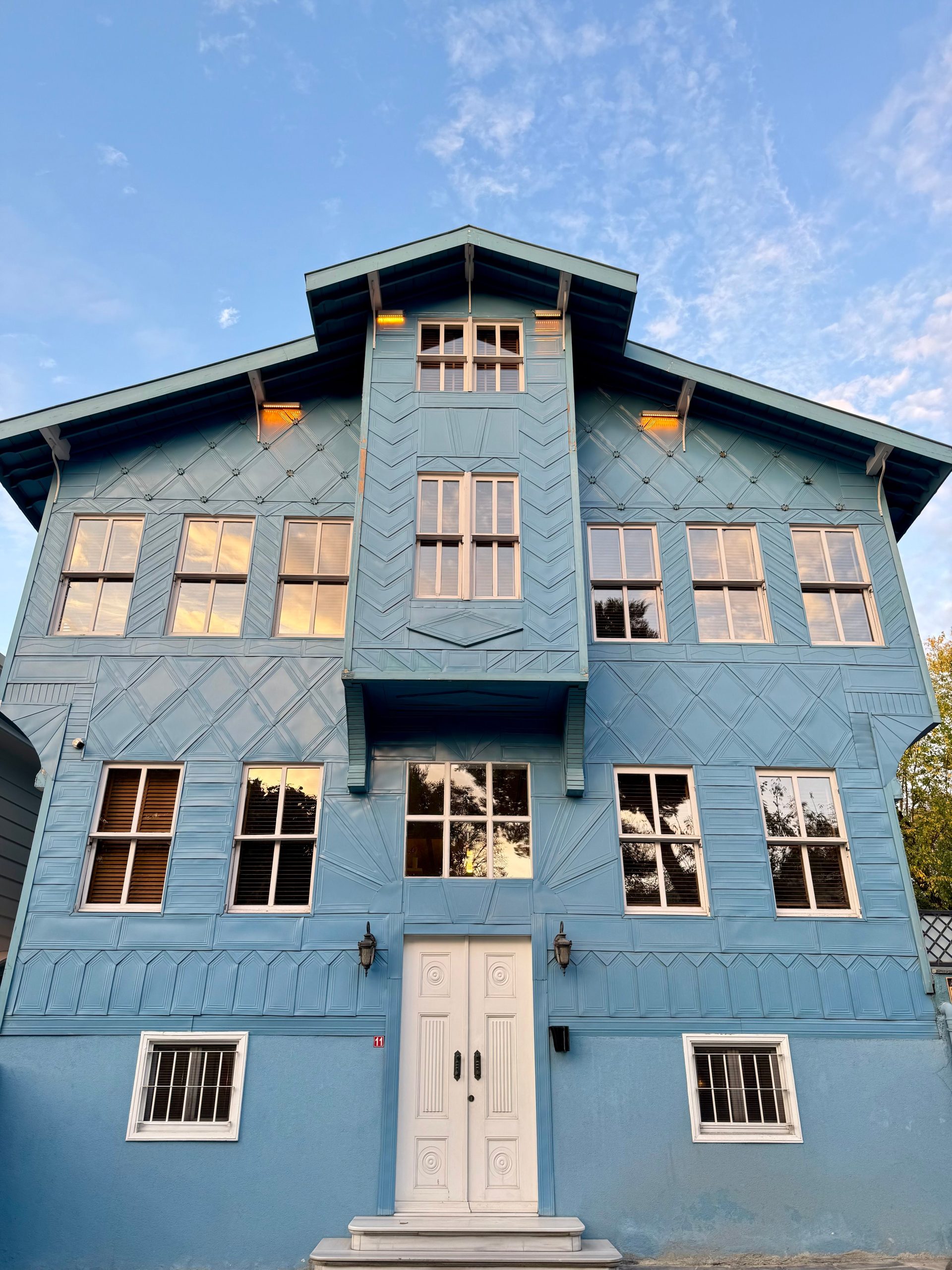 A picturesque blue wooden house with traditional architecture under a clear blue sky.