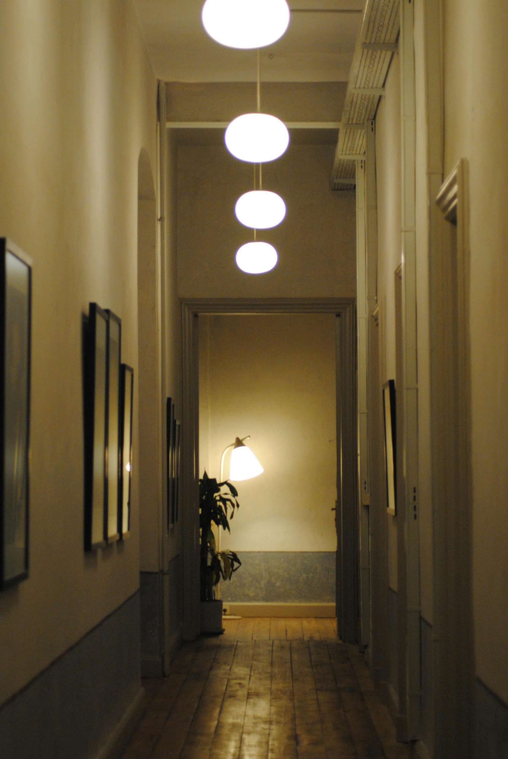 A quiet corridor with illuminated lamps and wooden floors, creating a calm and serene indoor atmosphere.