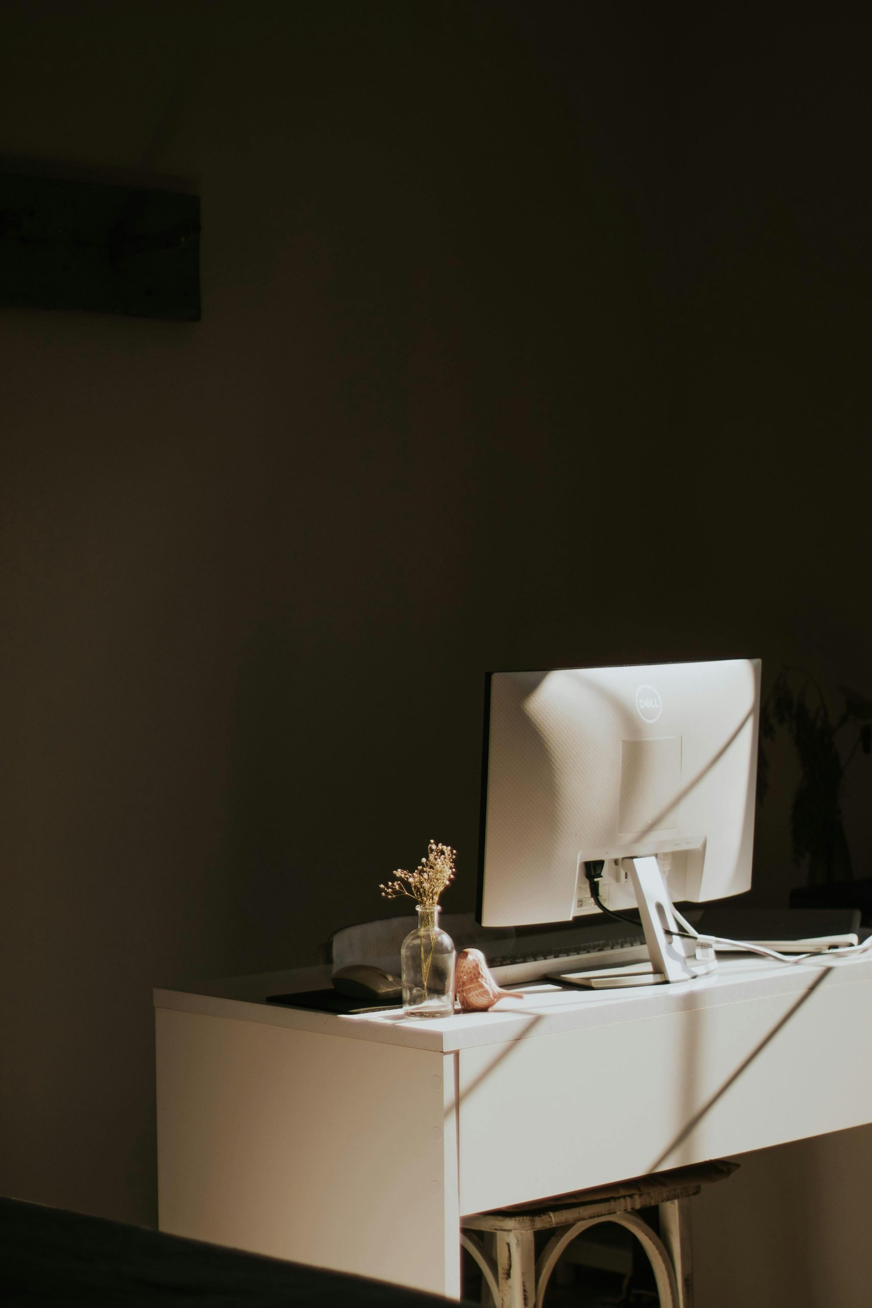A serene, minimalist home office with a sleek monitor and subtle decor in soft lighting.