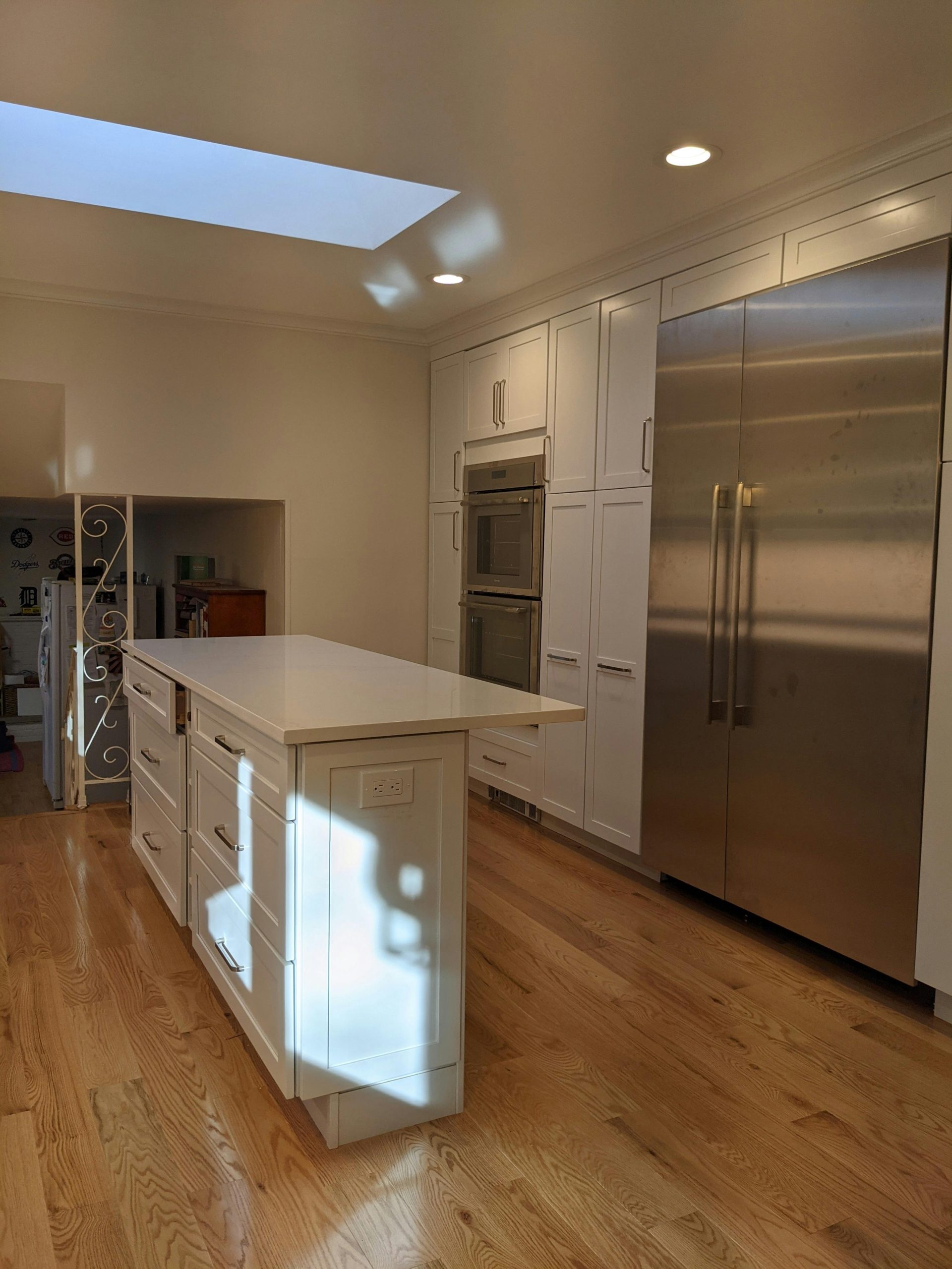 A sleek and modern kitchen interior featuring a skylight, island, and stainless steel appliances.