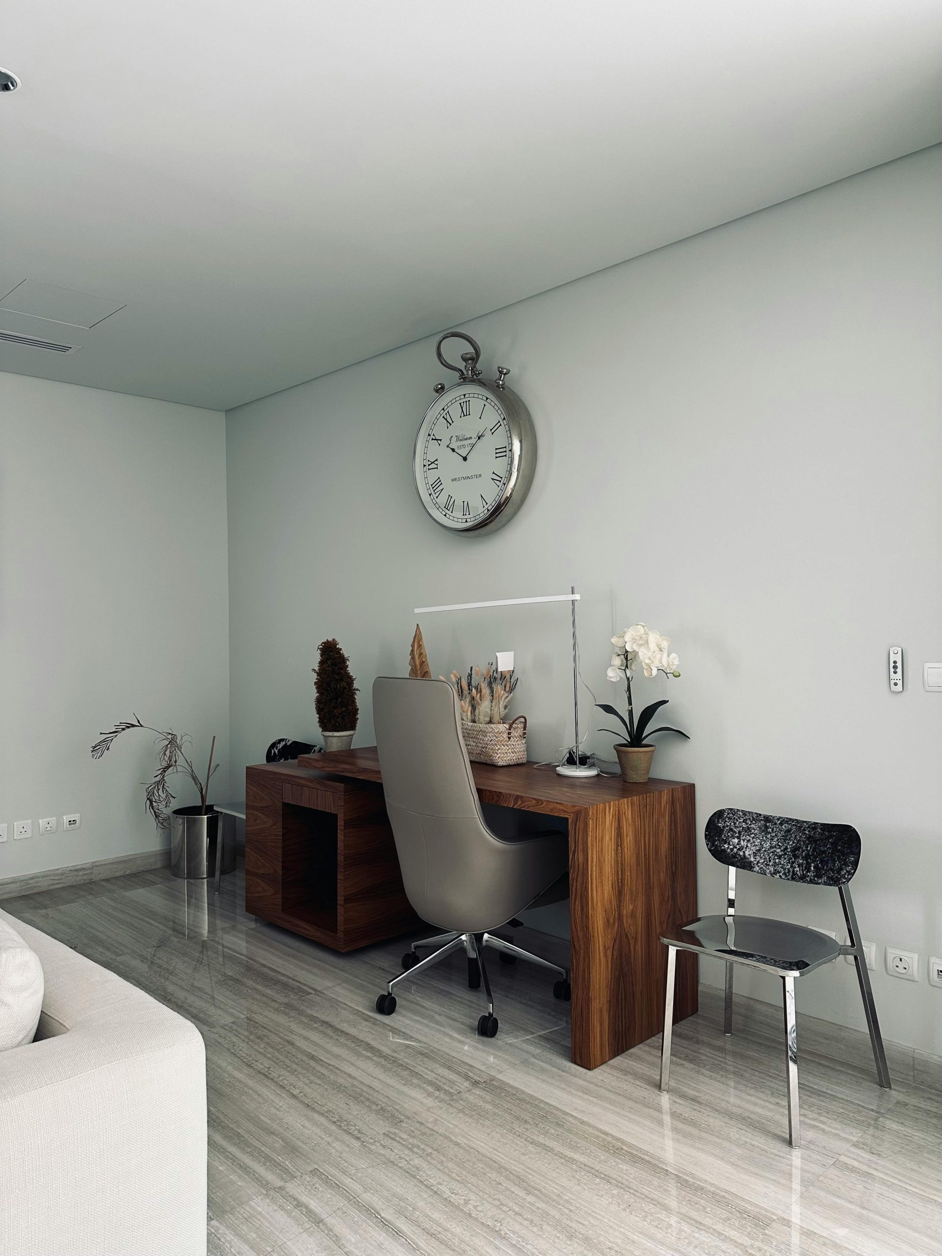 A sleek office space featuring a wooden desk with decor and a vintage clock.