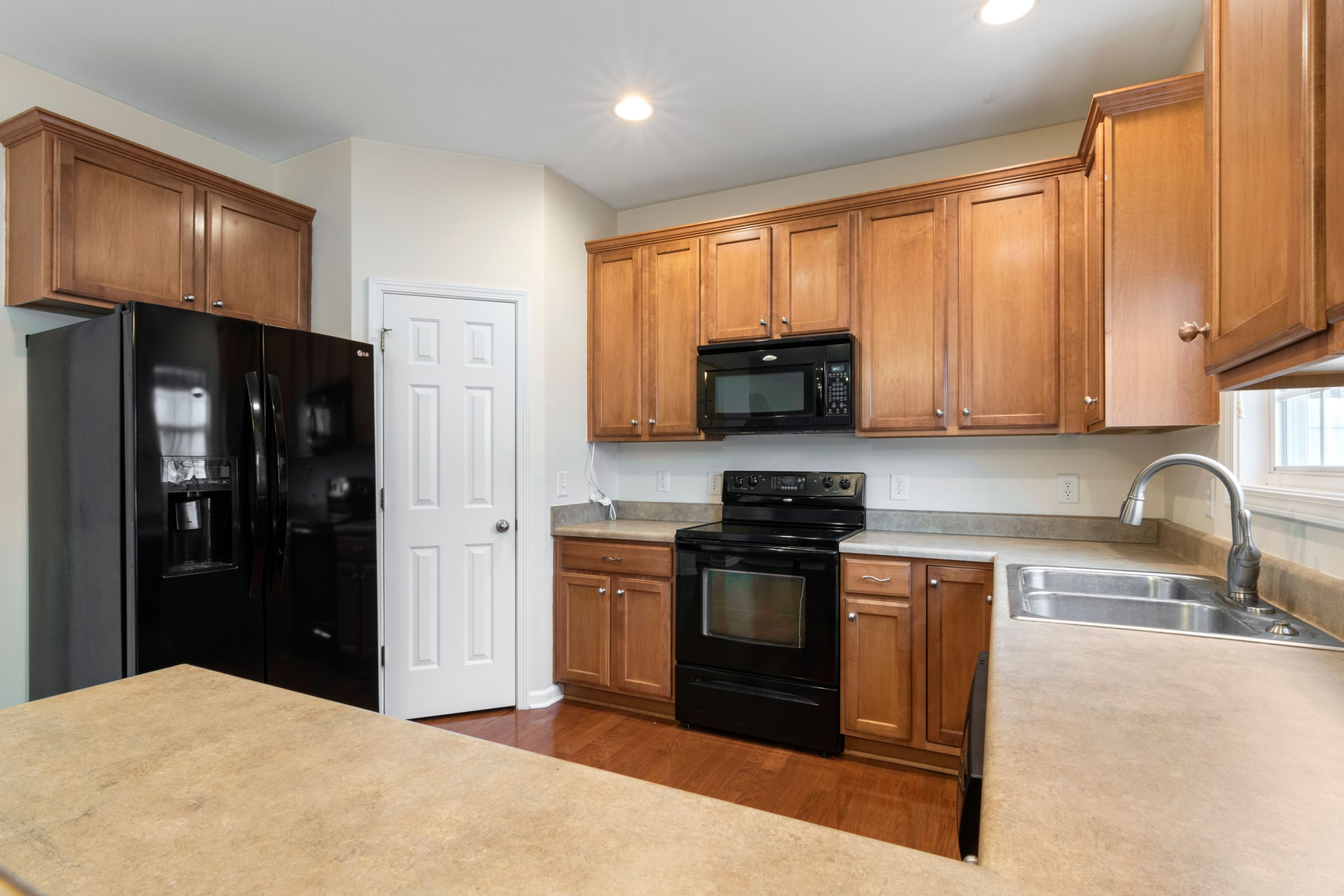 A spacious kitchen featuring wooden cabinets, black appliances, and a sleek countertop.