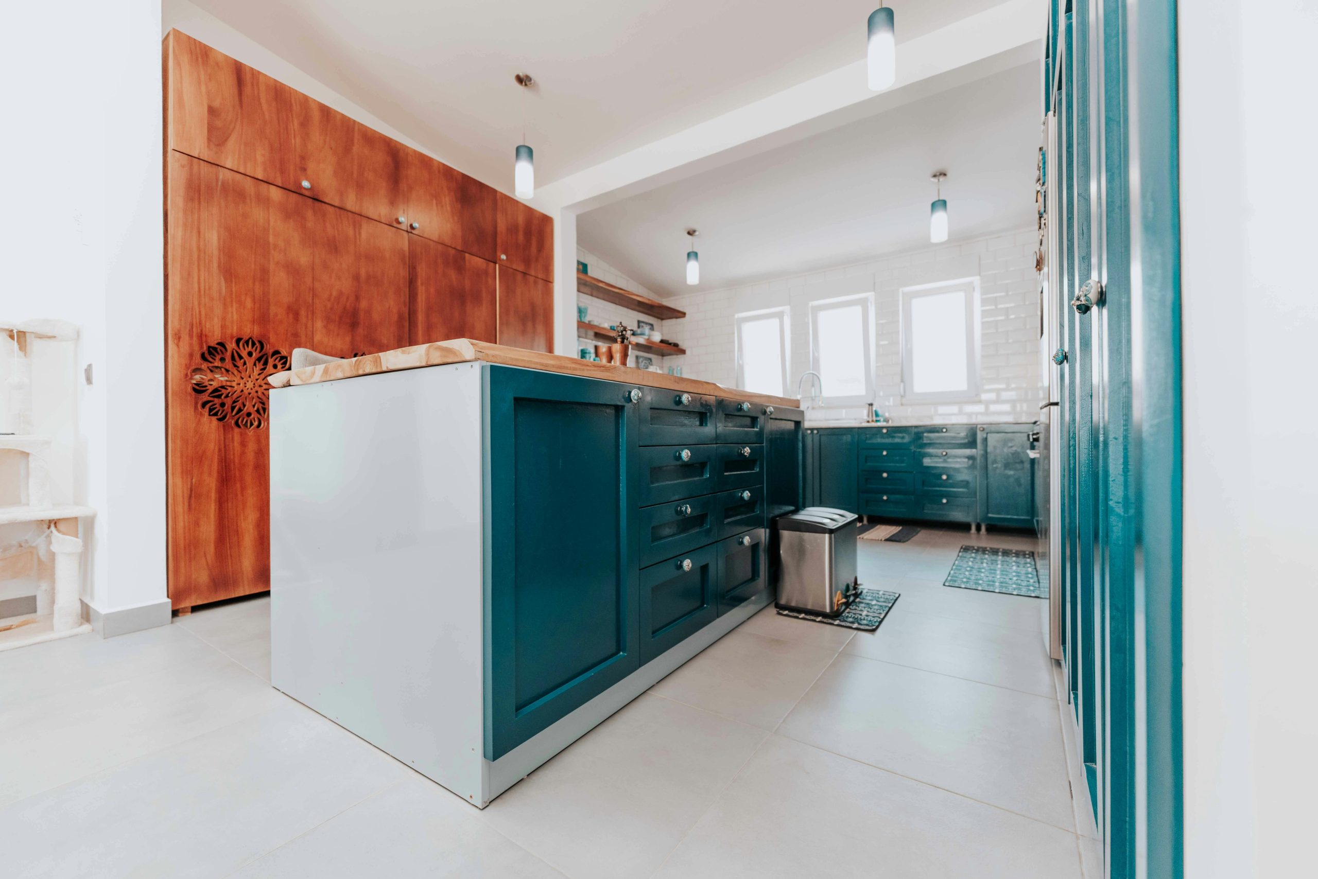 A spacious modern kitchen with blue cabinets and wood accents, featuring ambient lighting.