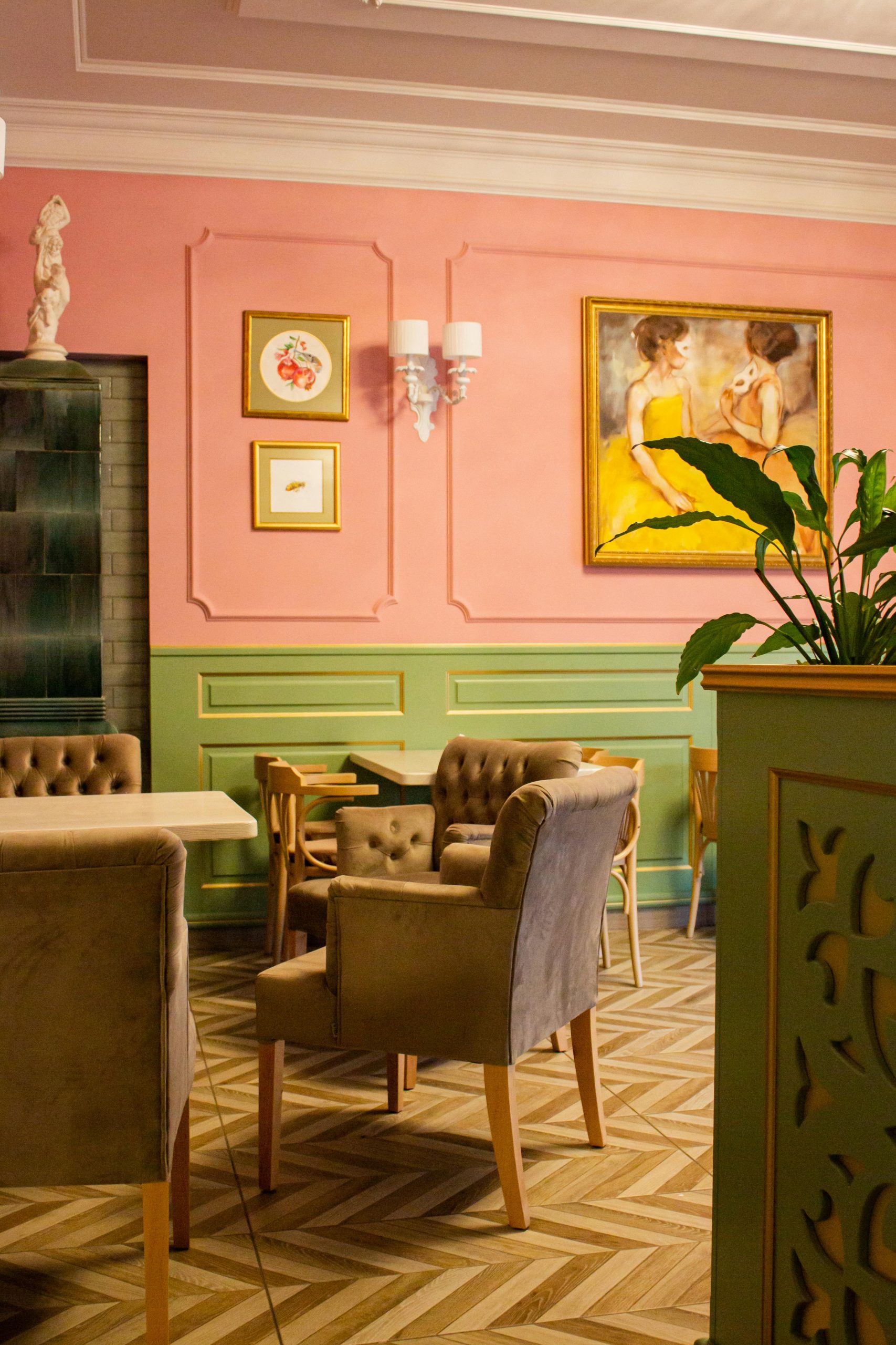 A stylish vintage cafe interior featuring pastel pink and green walls with elegant decor.