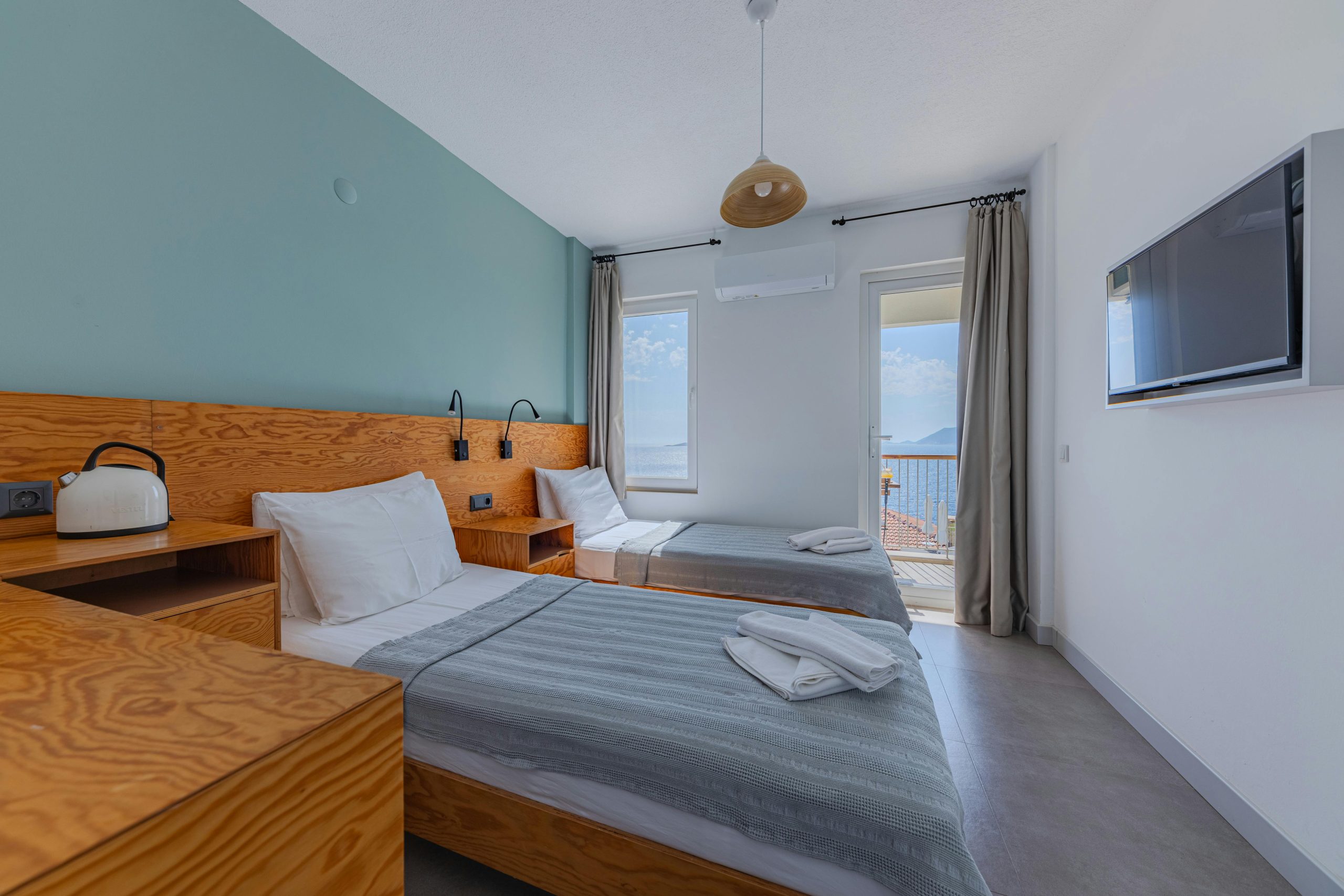 Bright hotel room featuring twin beds, modern decor, and a stunning sea view.