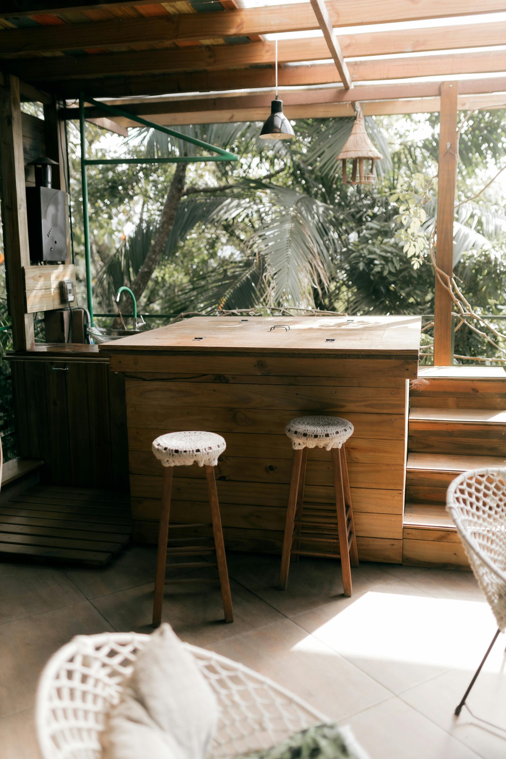 Charming outdoor bar with wooden stools and lush greenery, perfect for relaxation.
