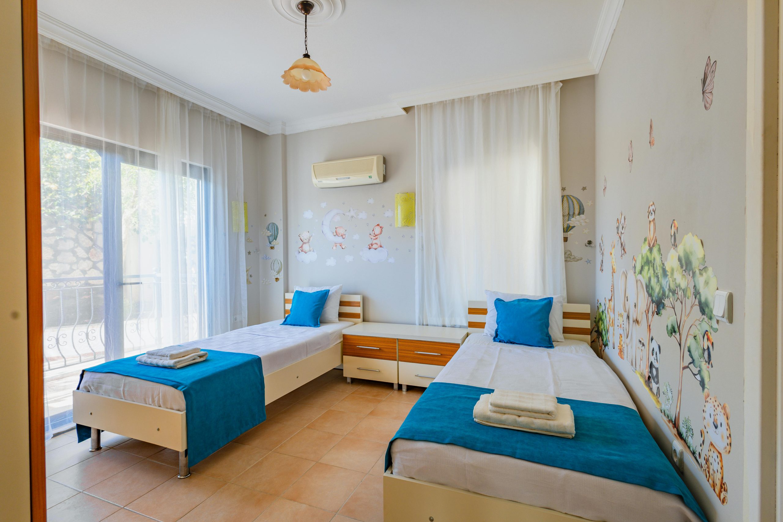 Comfortable twin bedroom with scenic wall art and natural light from balcony.
