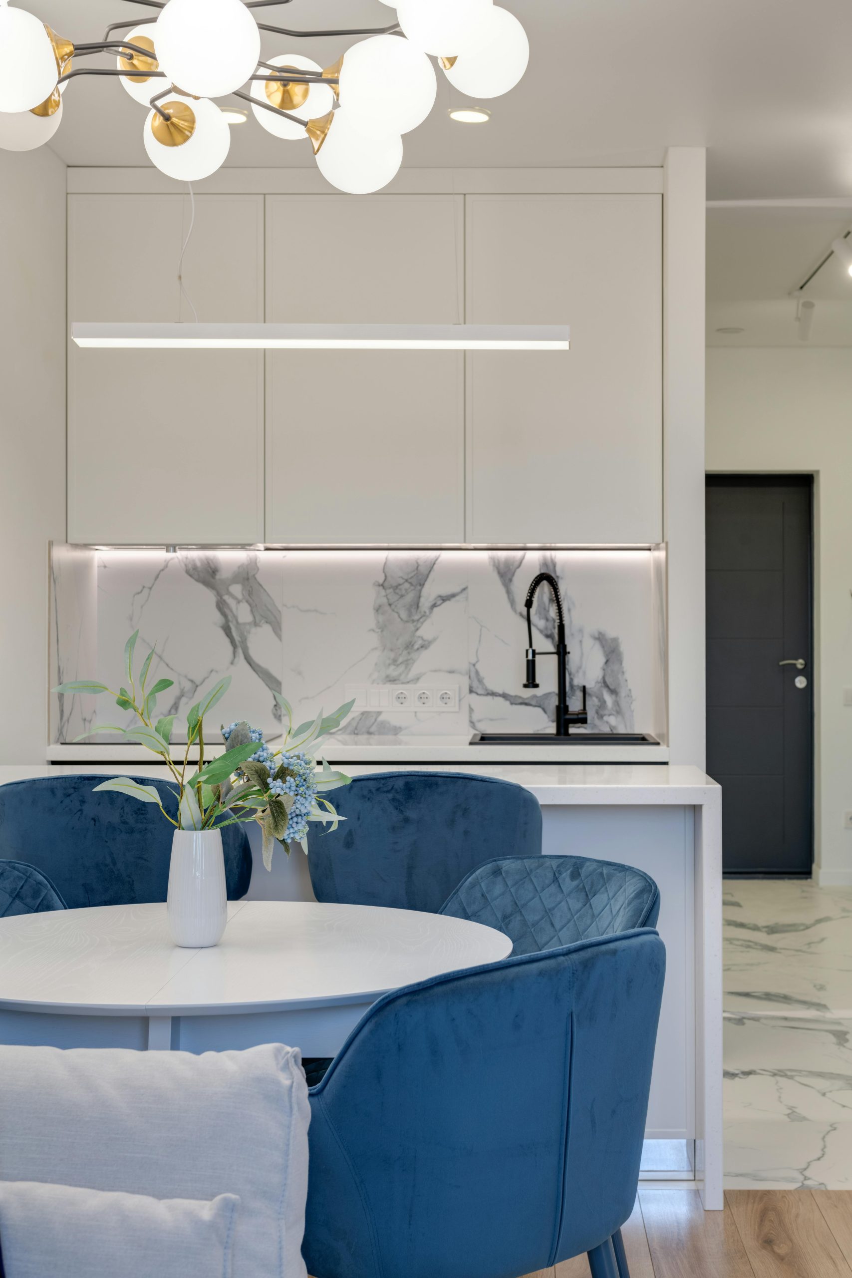 Contemporary kitchen design featuring blue chairs, round table, and marble elements.