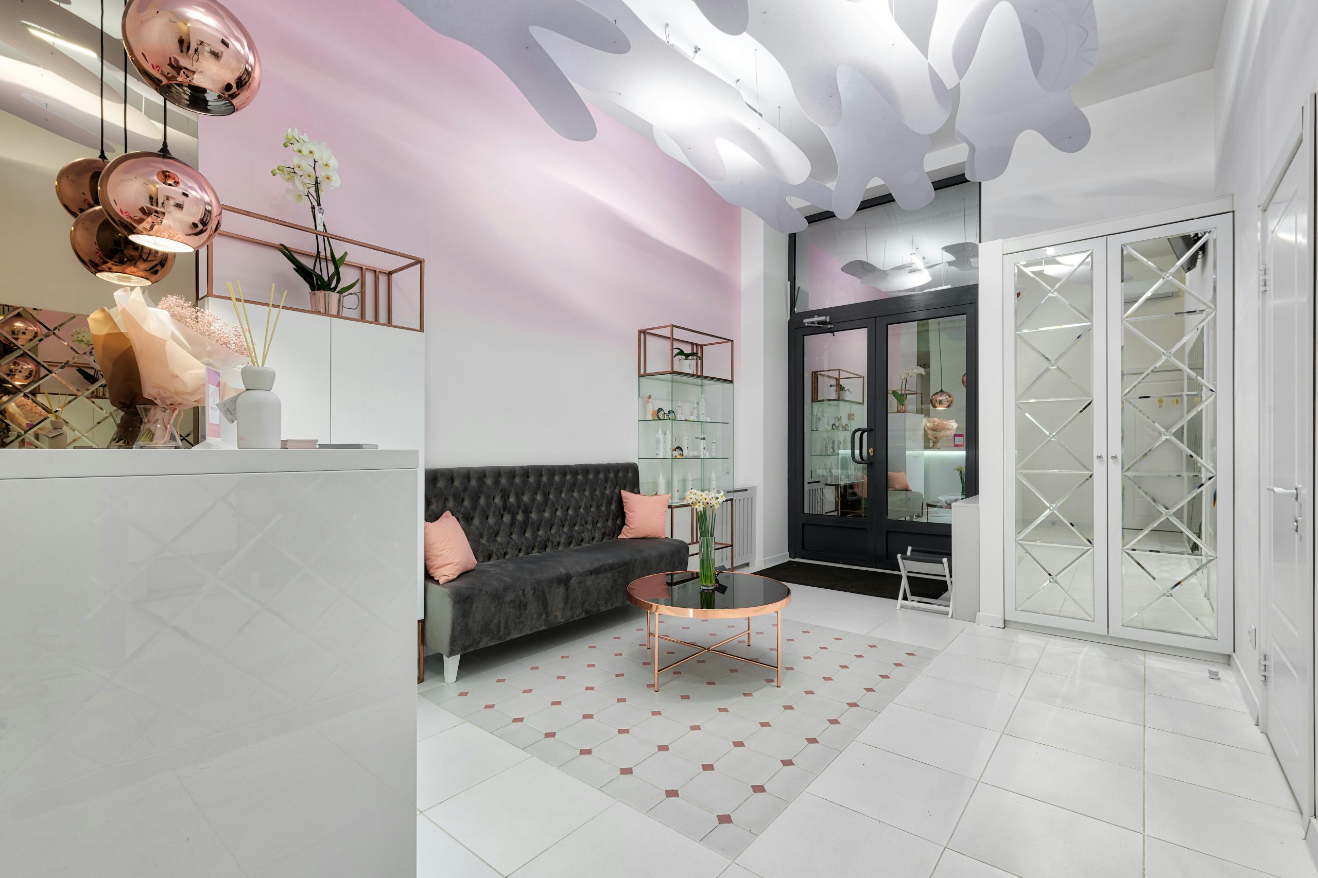 Contemporary lobby interior with sofa and table against doors illuminated by shiny lamps above tiled floor with ornament