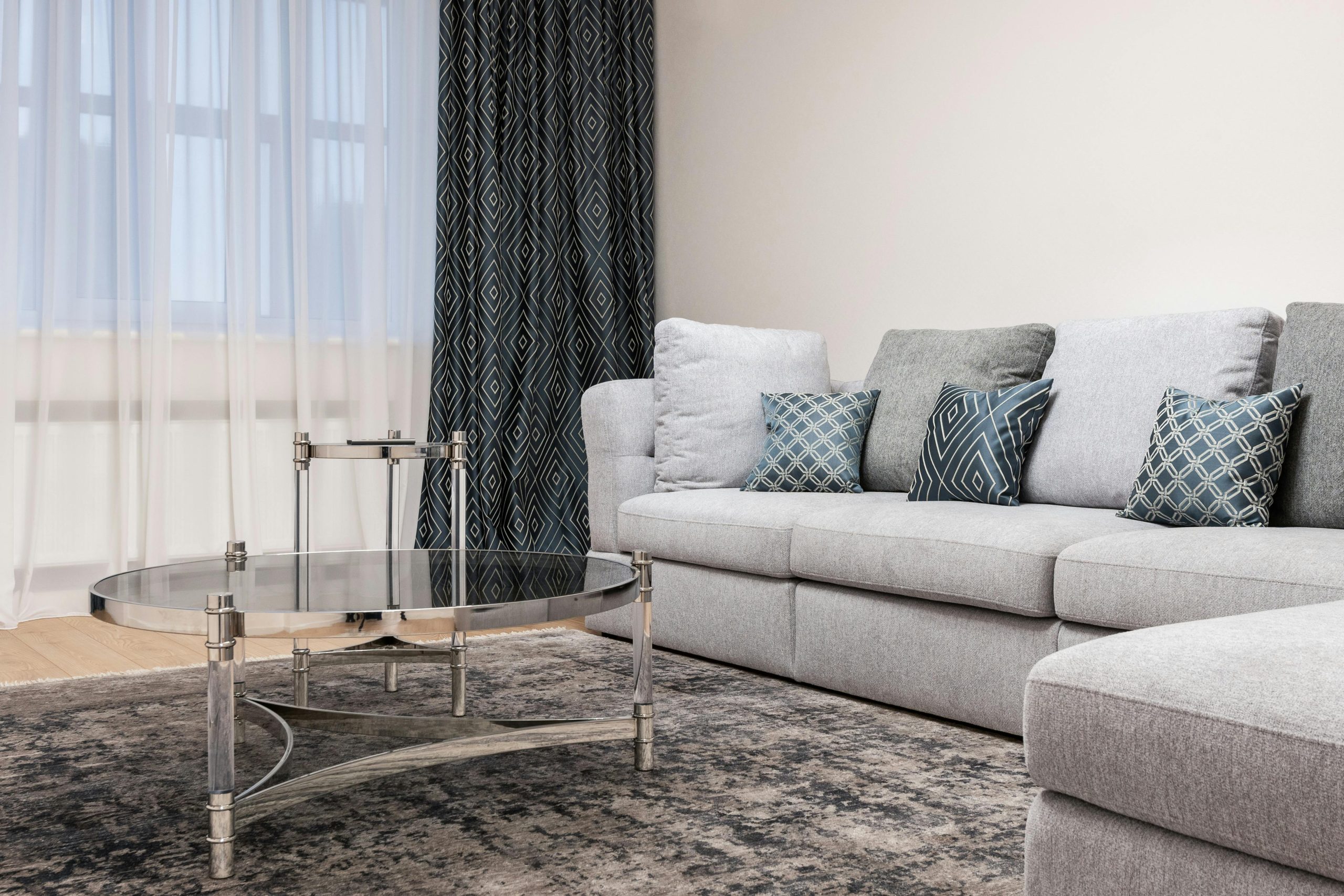 Couch with decorative cushions against metal and glass tables on rug in light house room