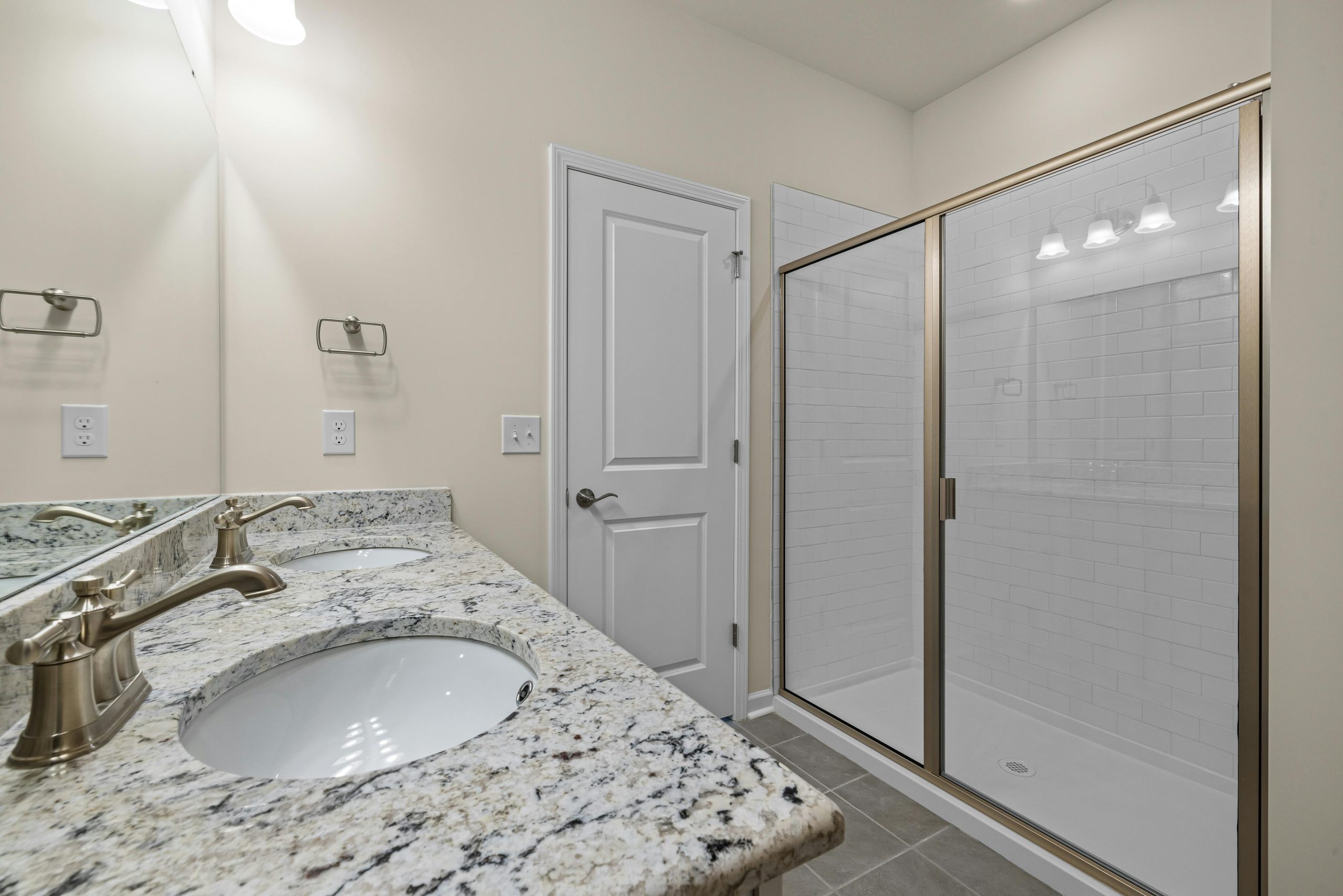 Elegant bathroom featuring granite countertops and a spacious glass shower enclosure.