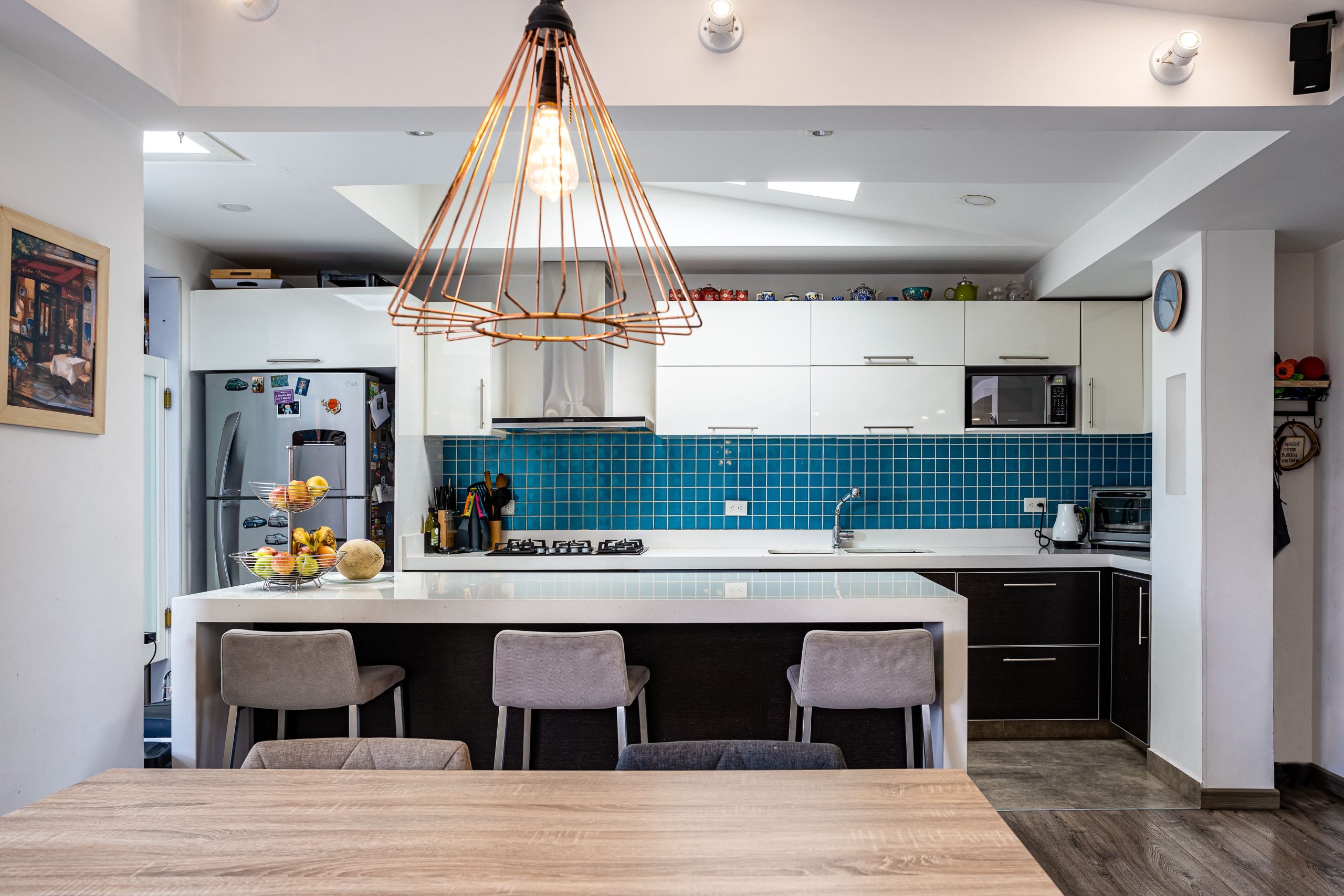 Elegant kitchen design featuring a blue tile backsplash, wooden accents, and contemporary lighting.