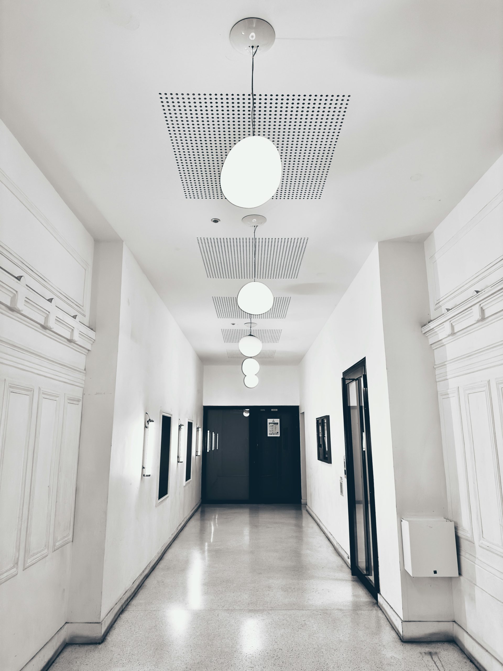 Elegant minimalist corridor with white walls and hanging round lights.