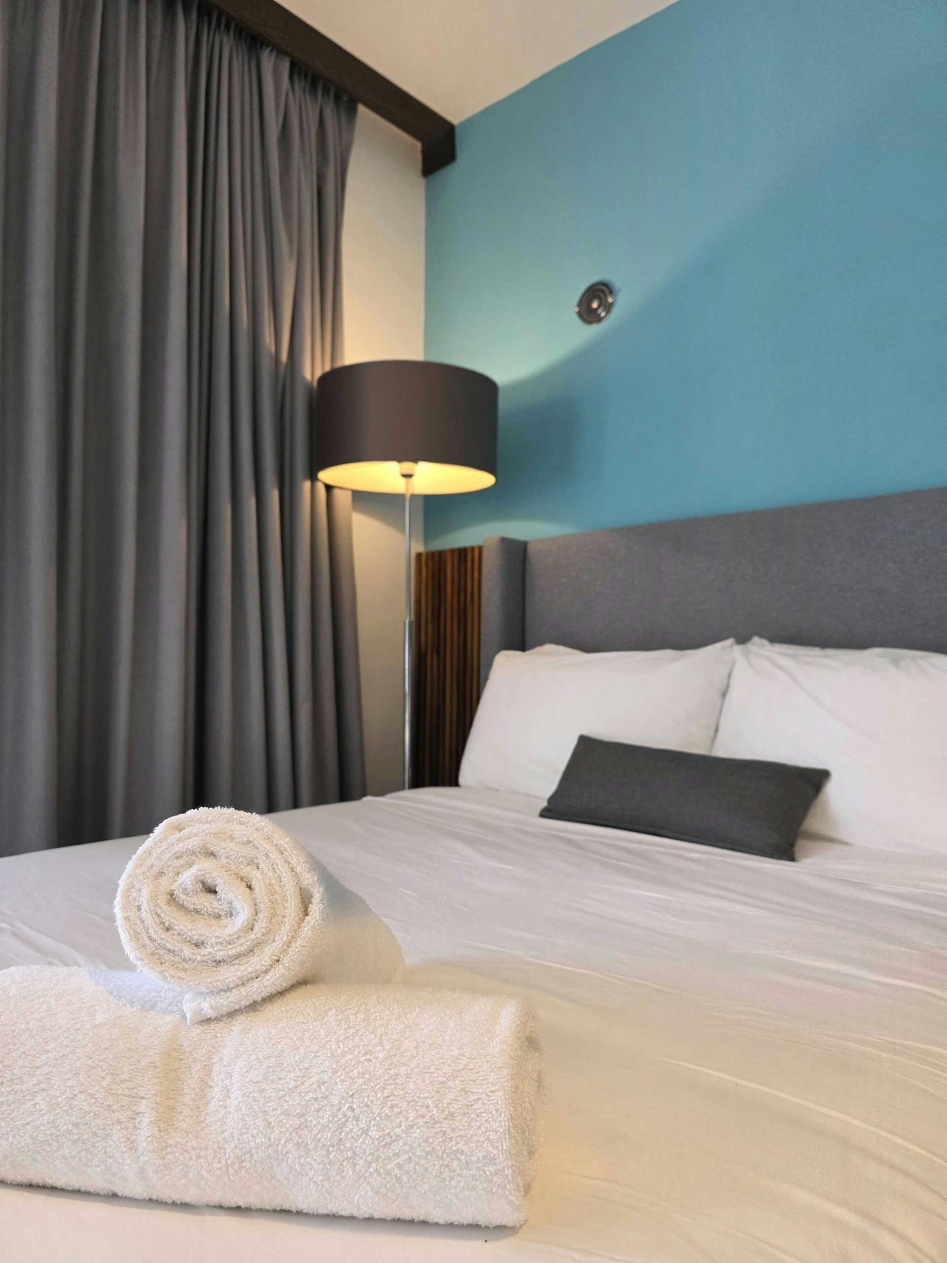 Inviting hotel room featuring plush bedding, rolled towels, and warm lighting.