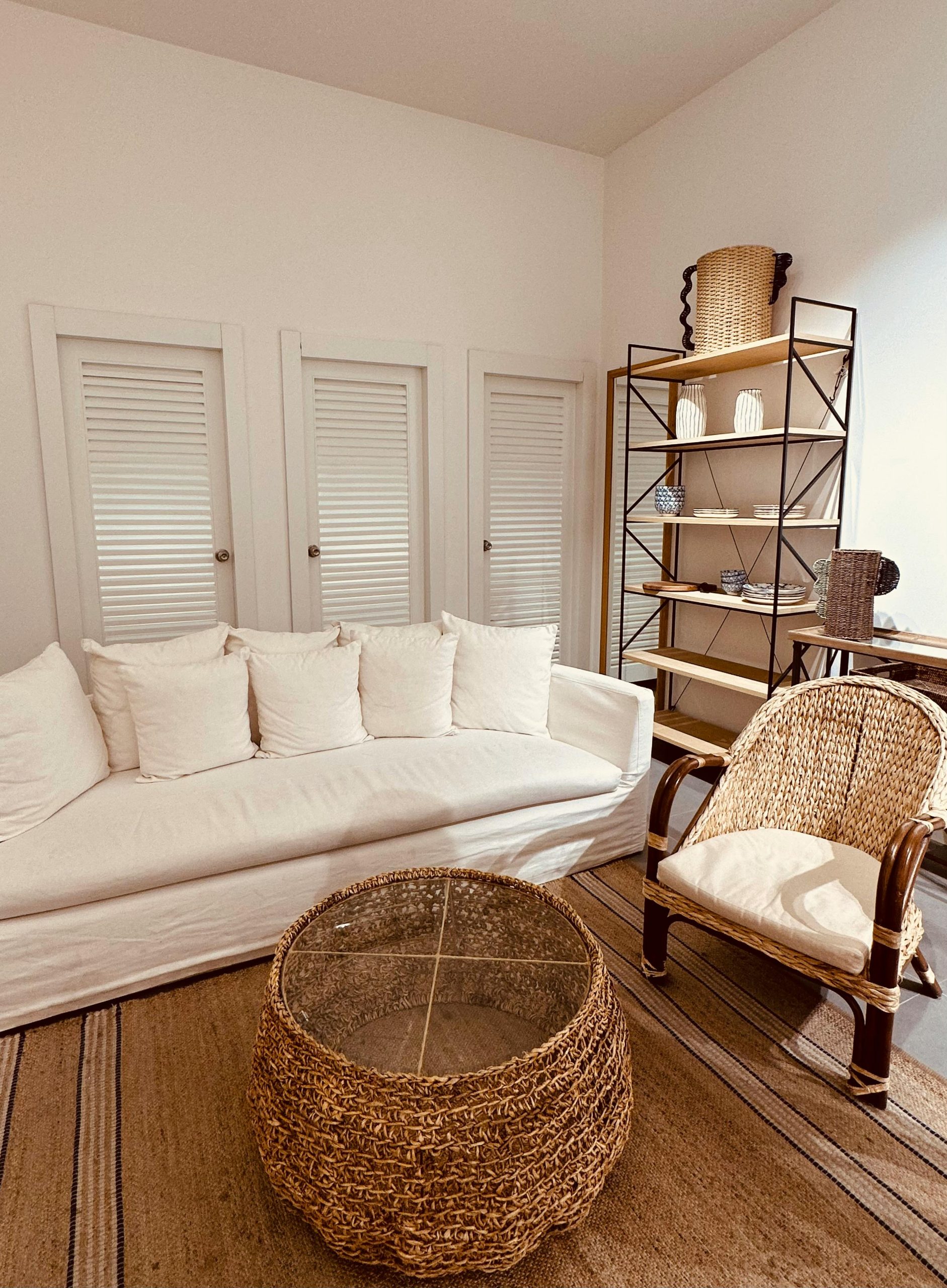 Inviting living room featuring a white sofa, rattan armchair, and rustic decor with natural lighting.