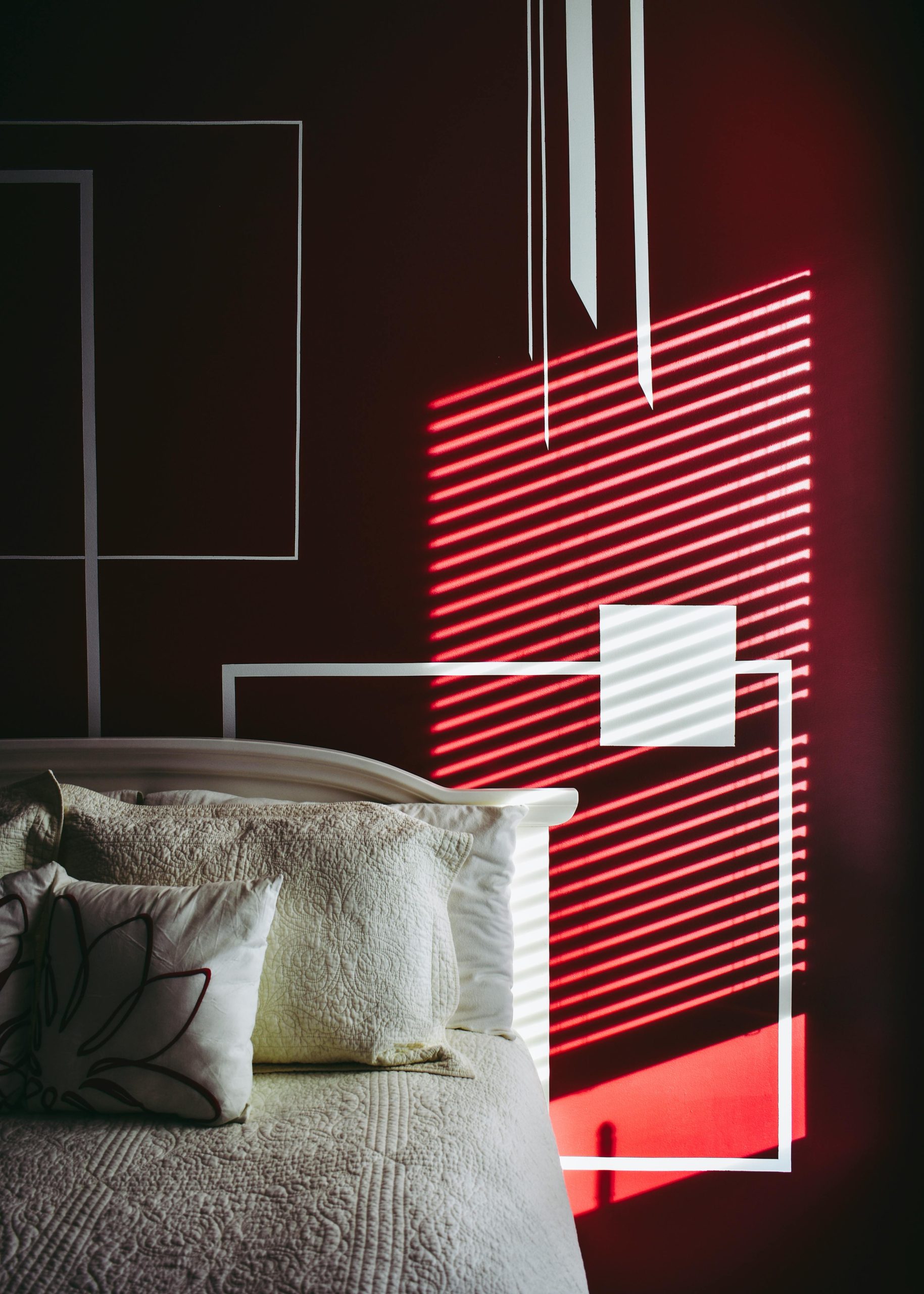 Modern bedroom showcasing striking light and shadow patterns on decor wall.