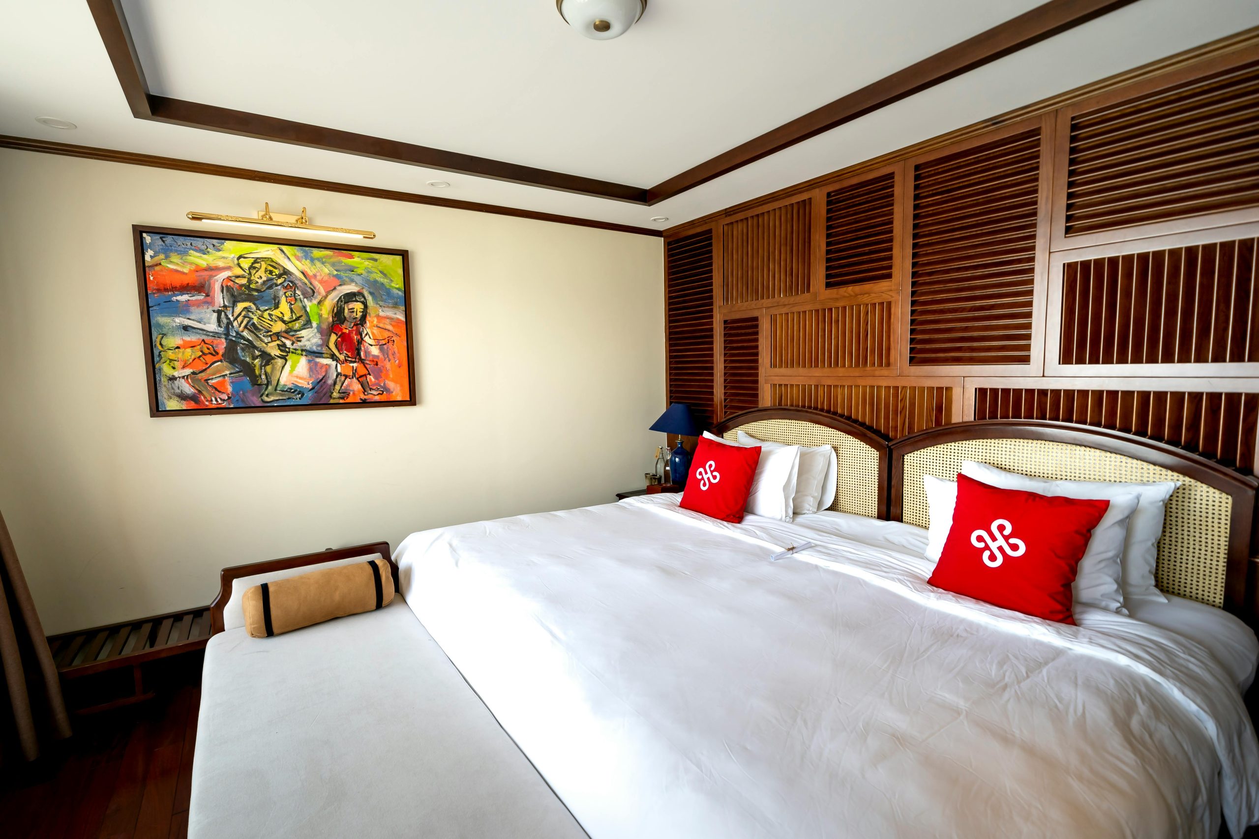 Modern hotel room featuring a large bed, vibrant artwork, and wooden accents, ideal for relaxation.