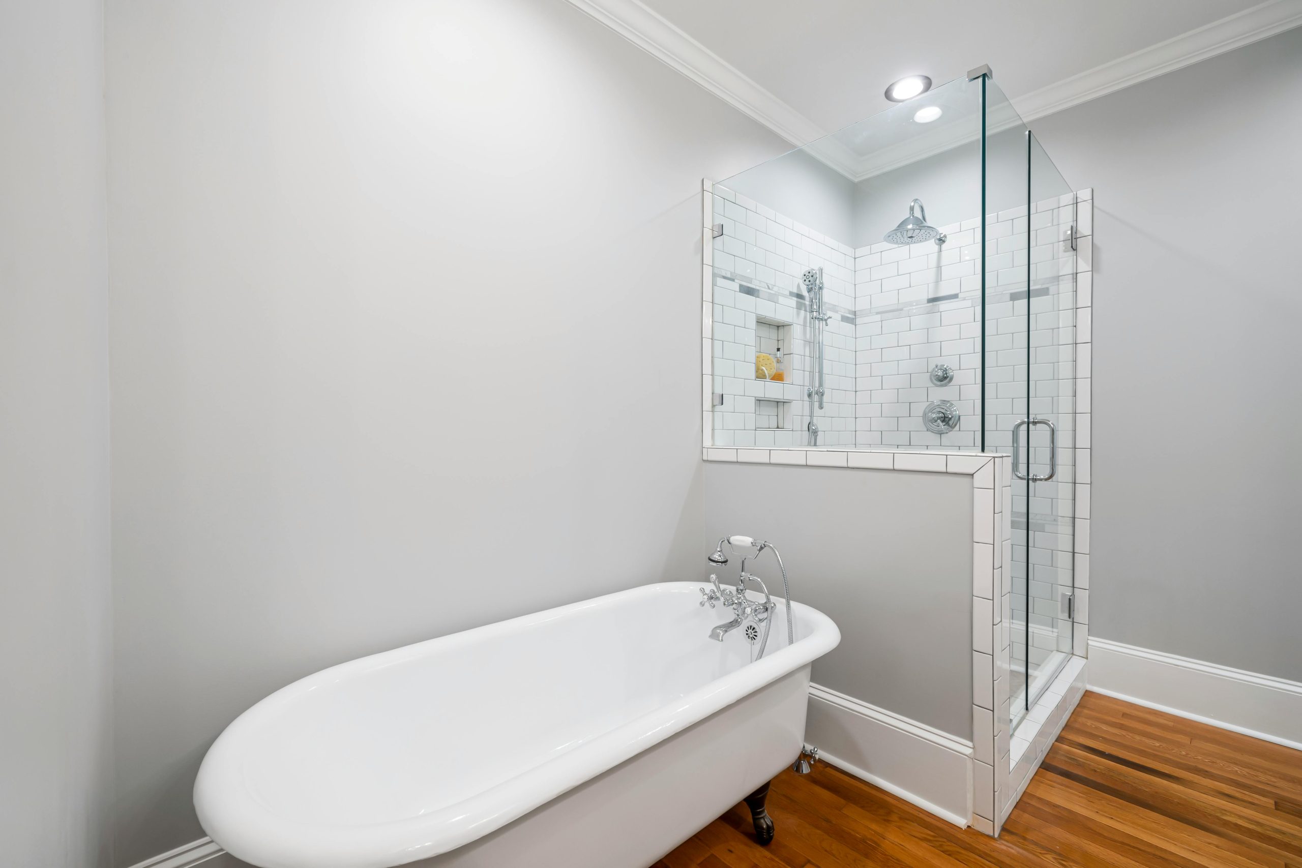 Modern minimalist bathroom featuring a luxurious clawfoot bathtub and a sleek glass-enclosed shower.