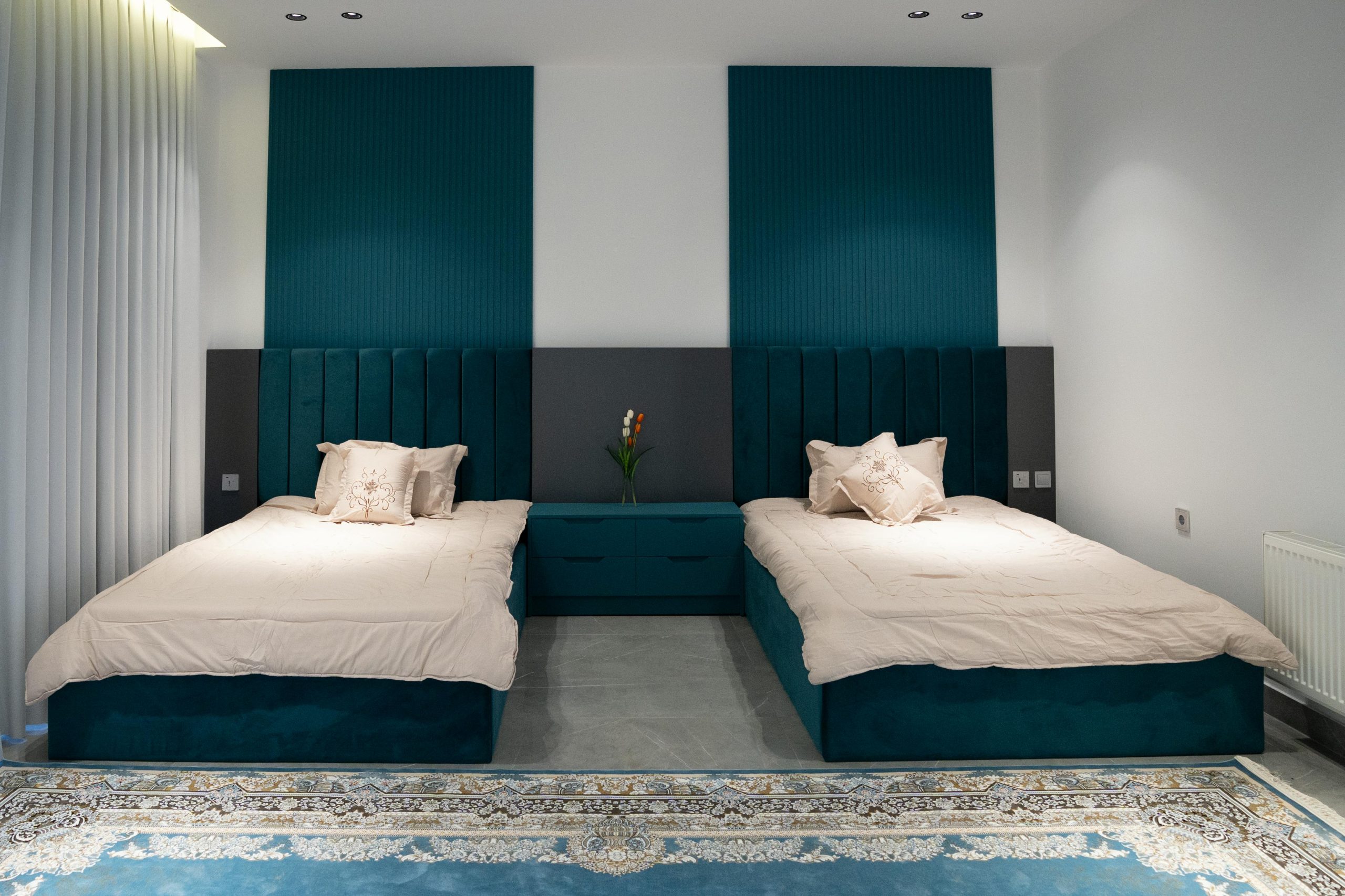 Modern twin bedroom with teal accents, stylish headboards, and cozy decor.