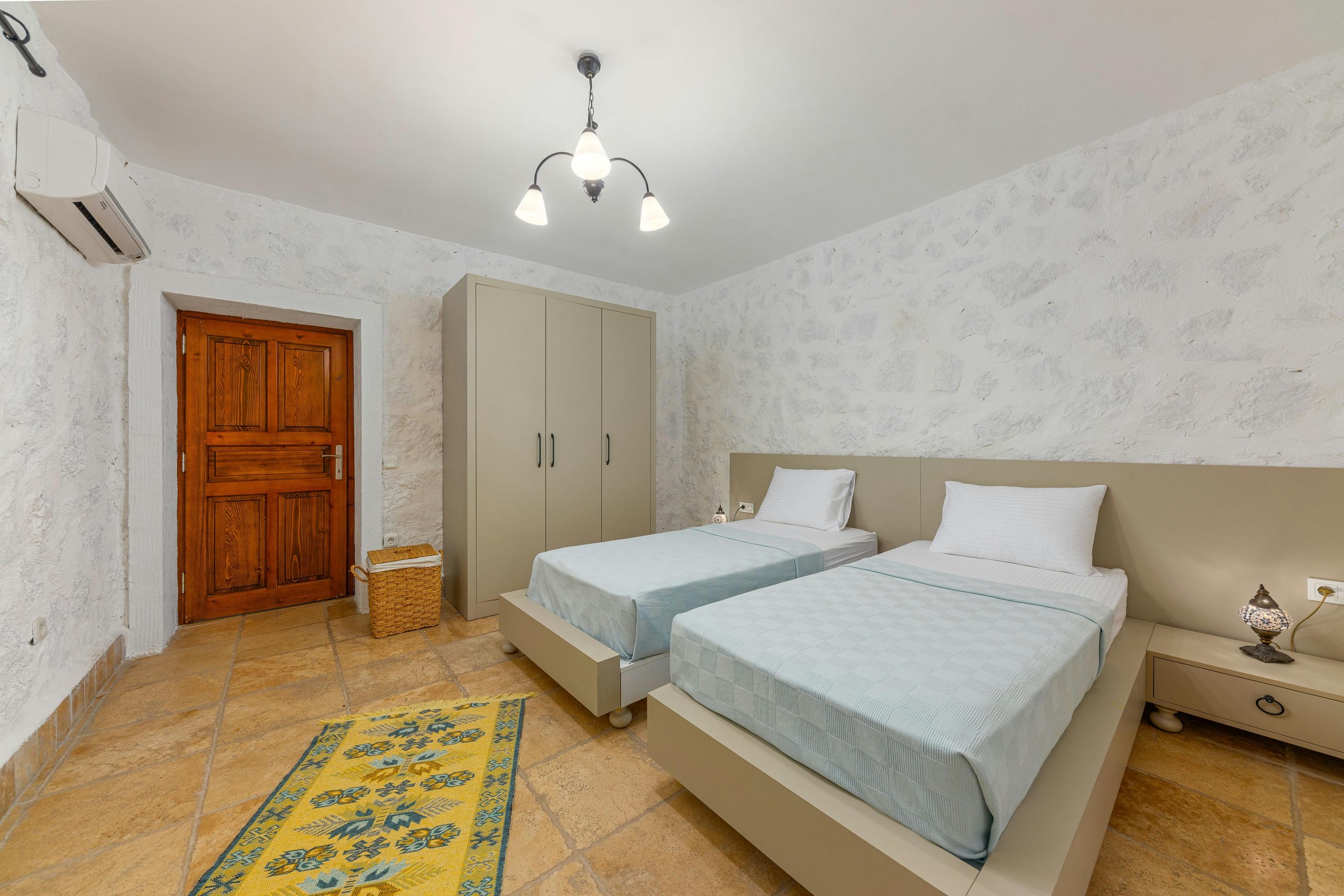 Spacious hotel room featuring twin beds, sleek wardrobe, and stylish decor, ideal for comfortable stays.