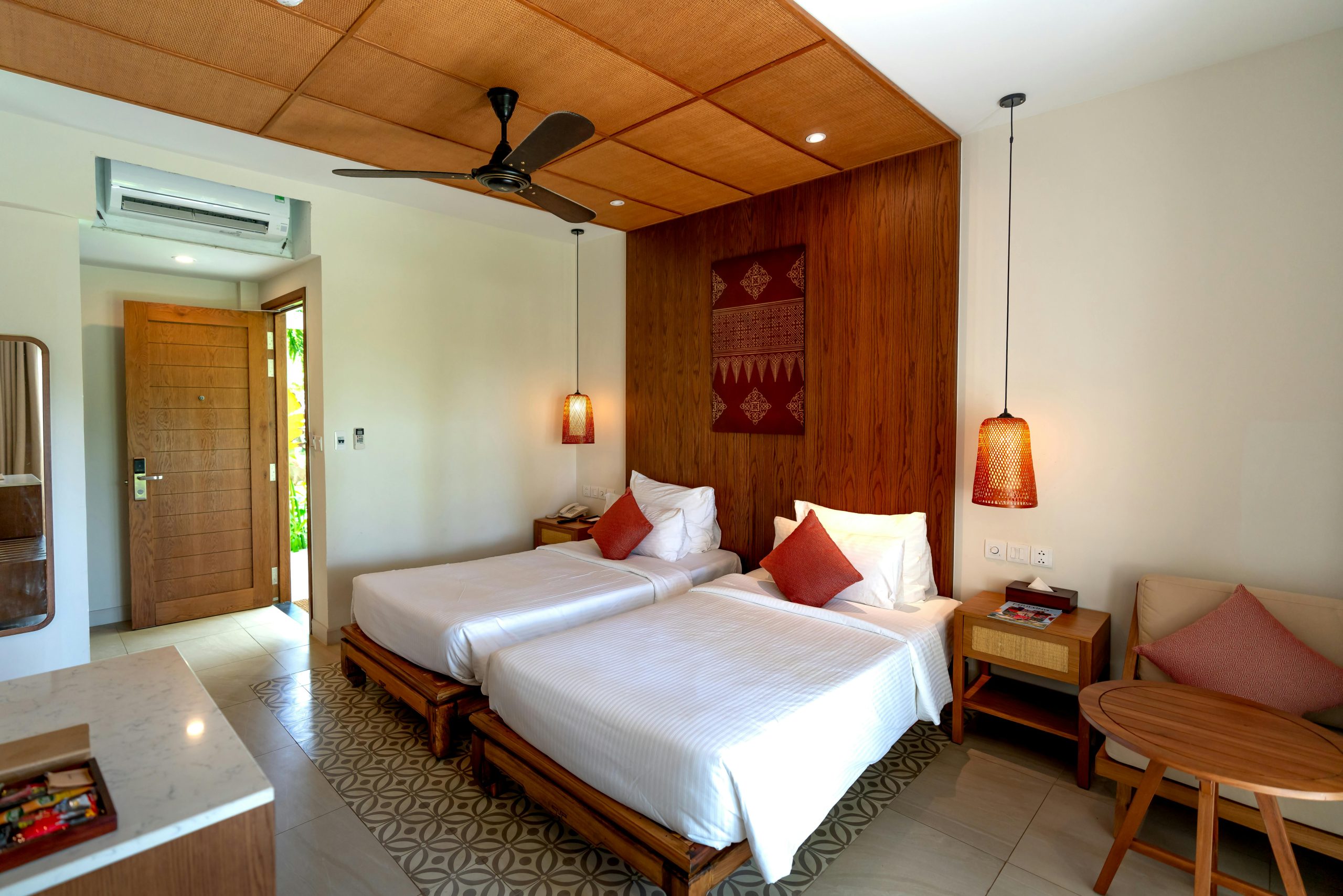 Spacious hotel room featuring twin beds, wooden decor, and modern amenities.