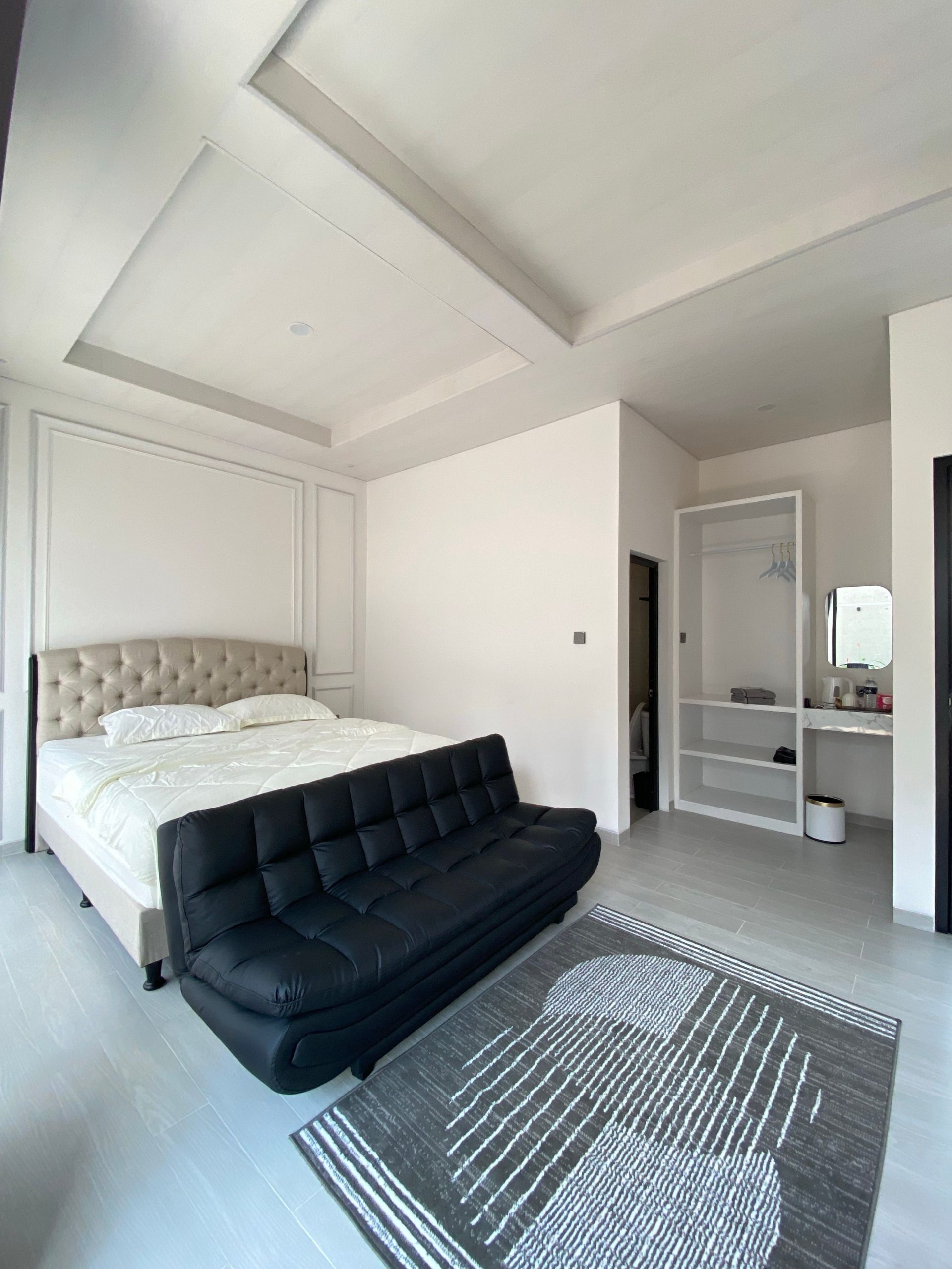 Spacious modern bedroom featuring elegant decor, minimal furniture, and monochrome themes with ample lighting.