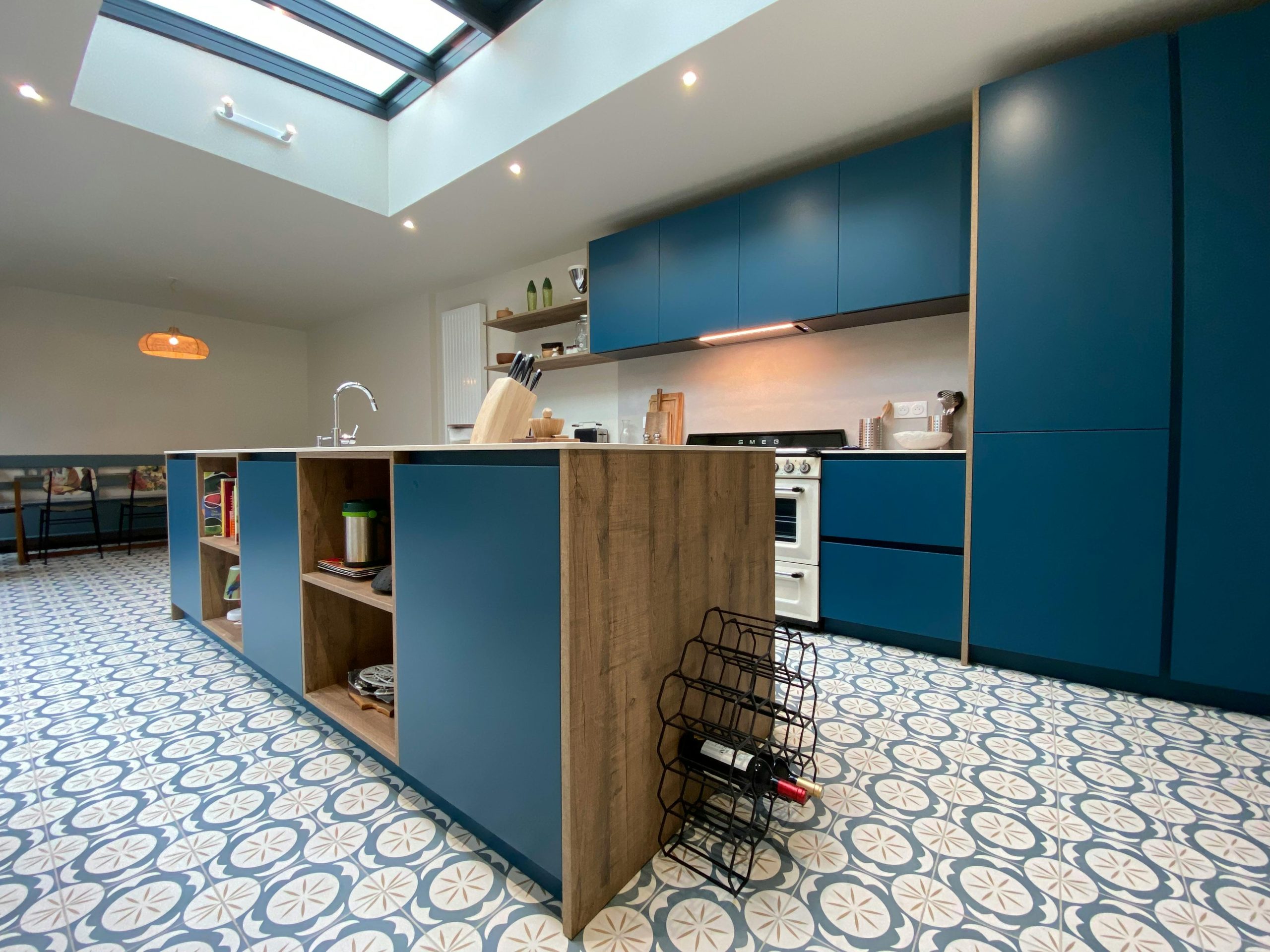 Spacious modern kitchen with blue cabinets, skylight, and patterned floor tiles.