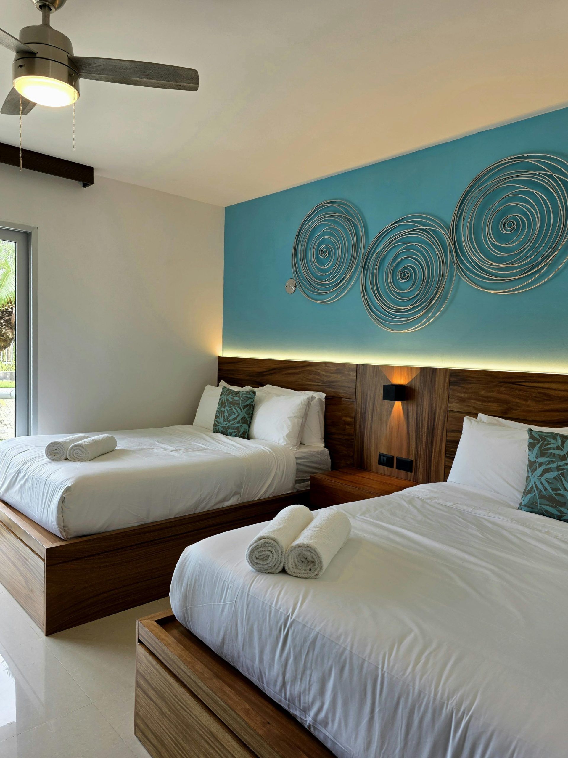 Stylish hotel room with twin beds, artistic decor, and ample natural light creates a relaxing atmosphere.