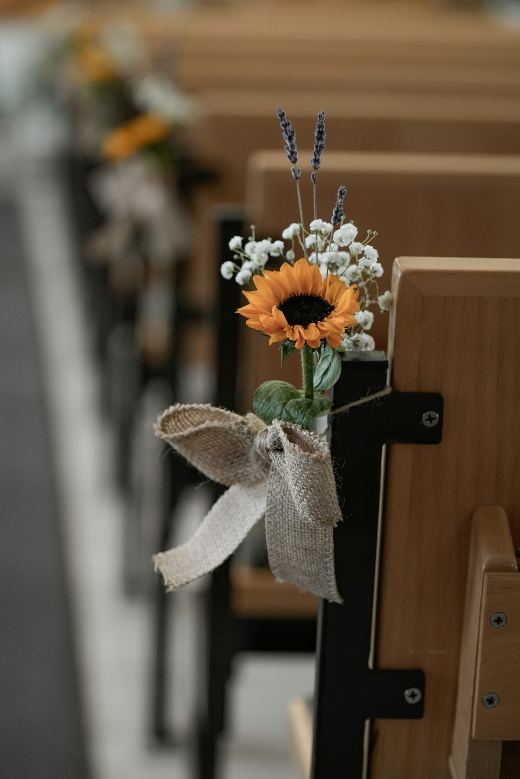 Sunflower and lavender pew decoration on wooden church bench