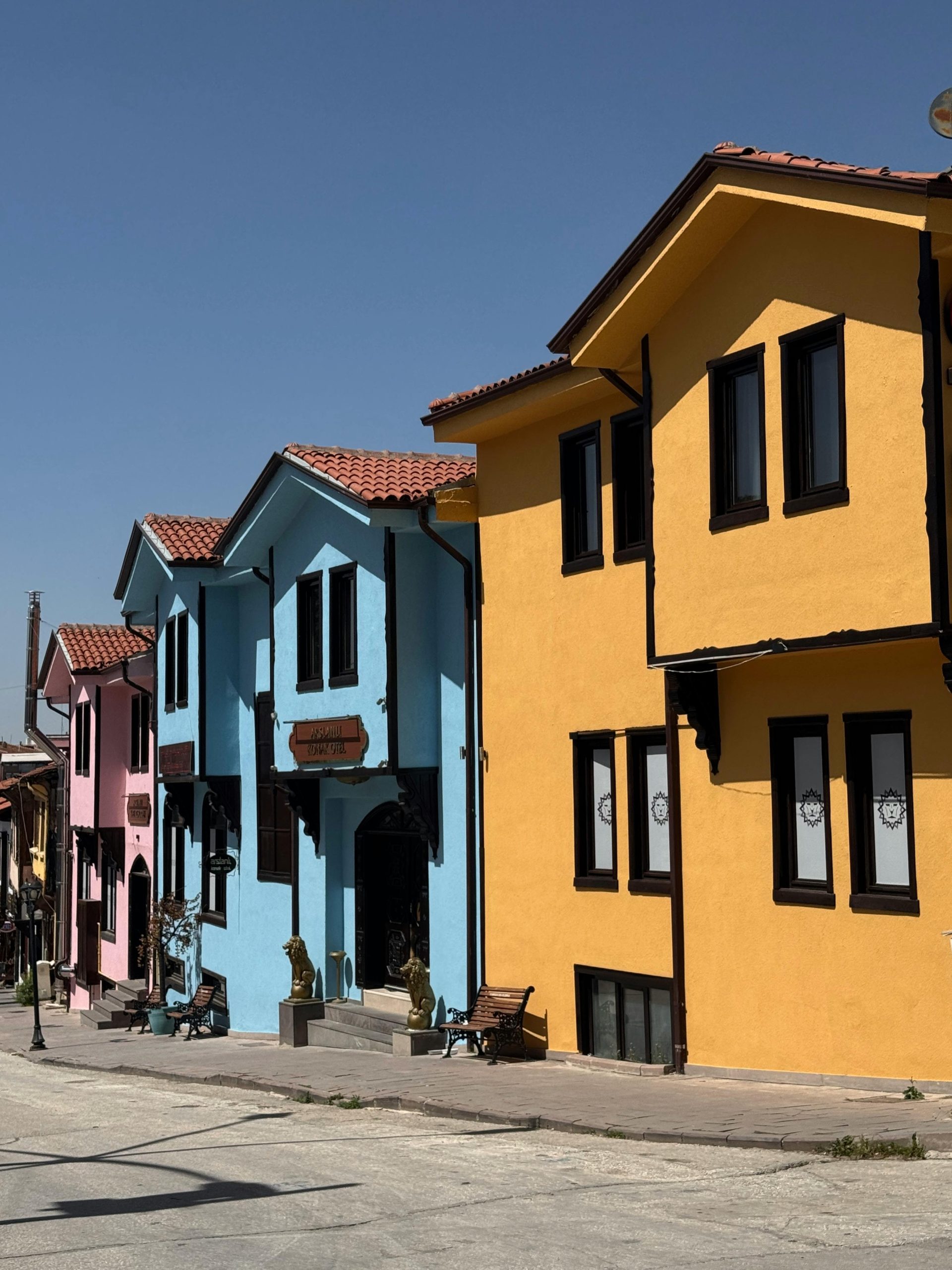 Vibrant pastel-colored houses line a charming street under clear blue skies.