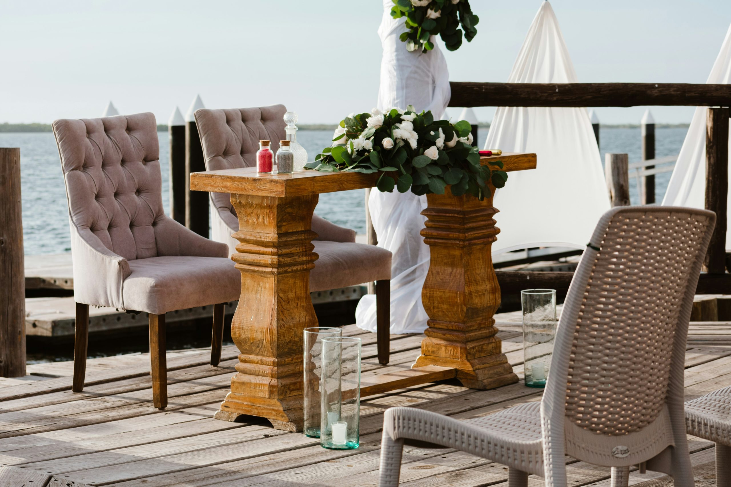 Wedding ceremony setup on a wooden deck by the water.