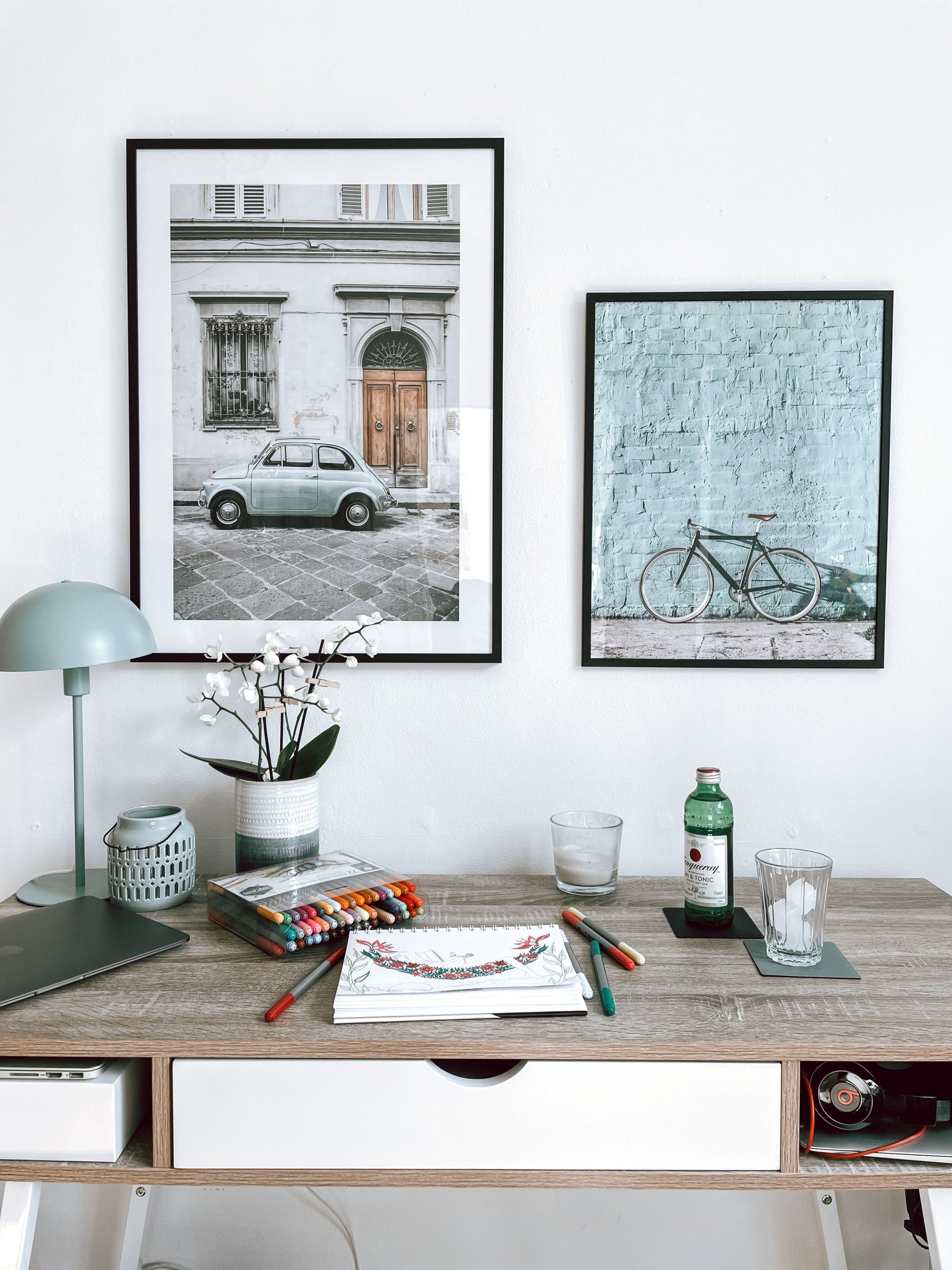 A beautifully arranged minimalist home office with framed art and stationery on a wooden desk.