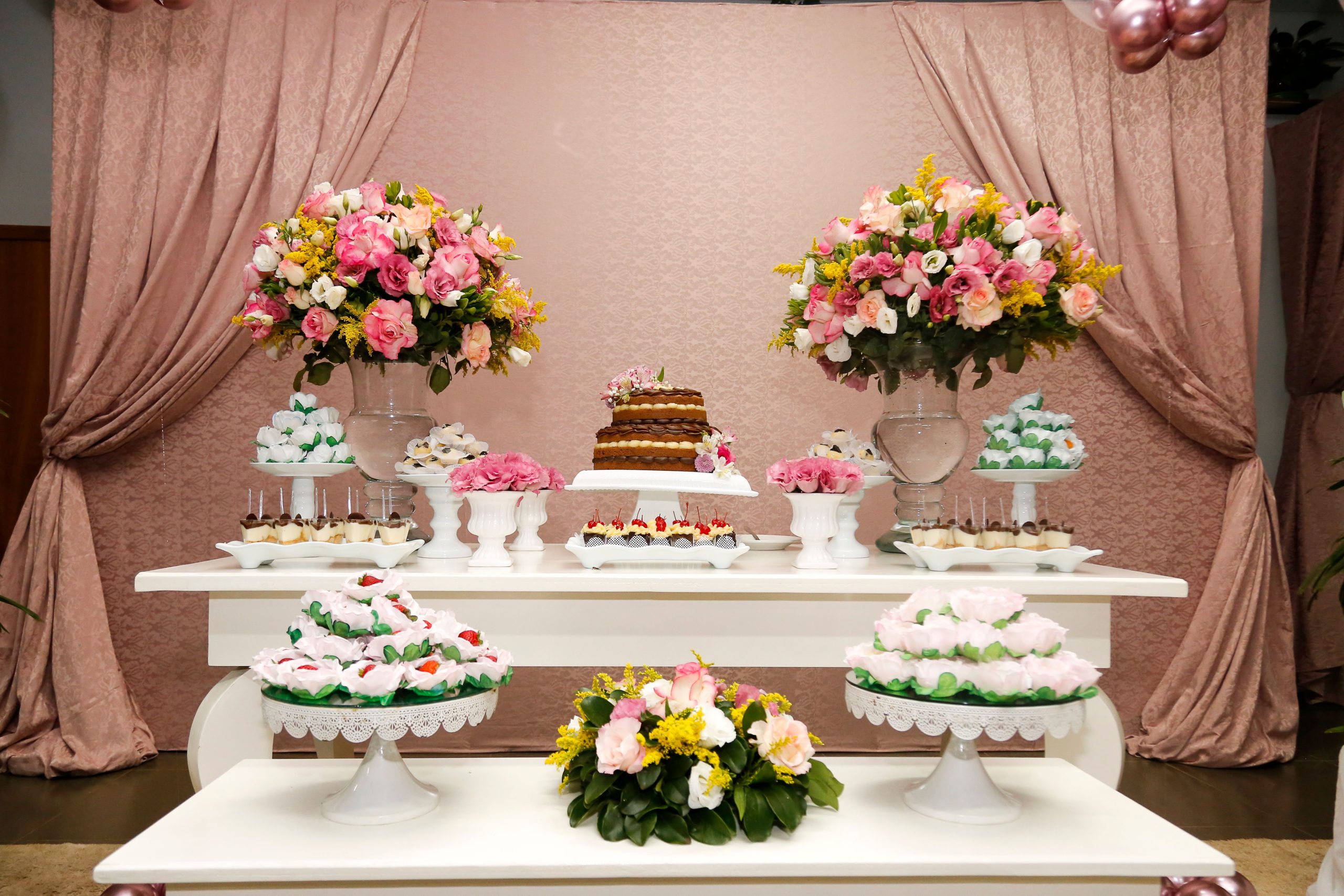 A beautifully decorated dessert table with floral arrangements, cakes, and pastries, perfect for celebrations.