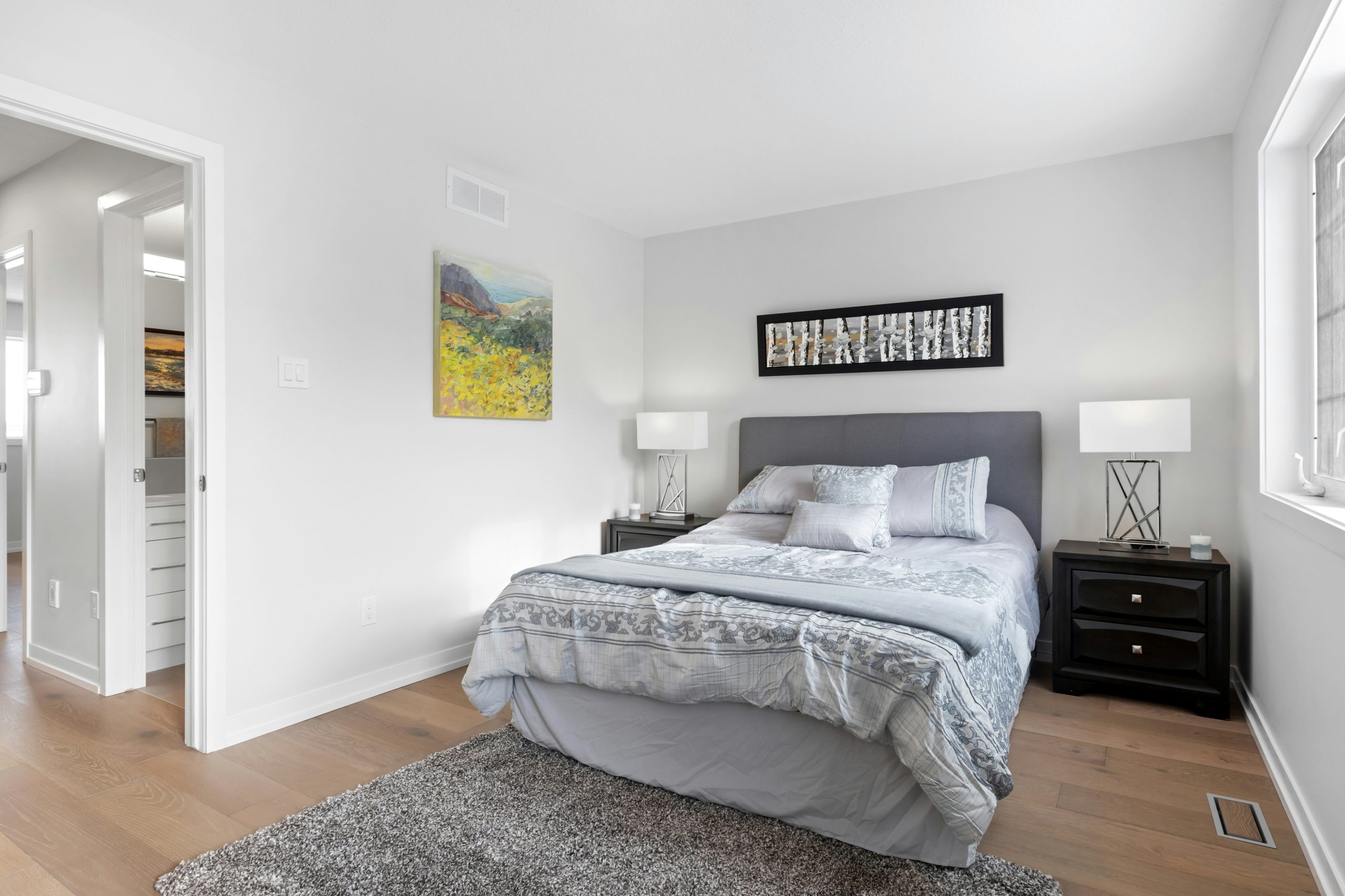 a bedroom with a bed, nightstands and a painting on the wall