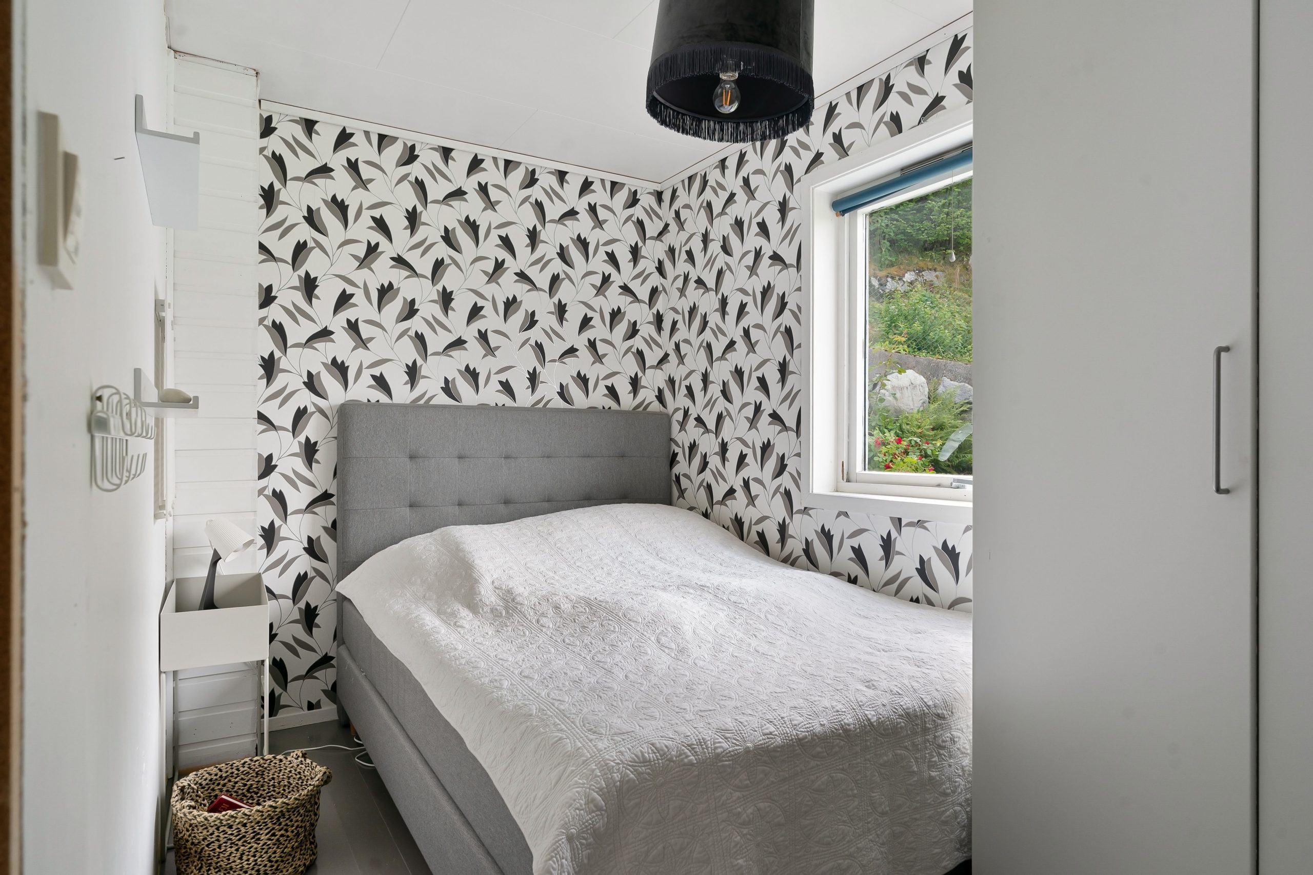 A bright, stylish bedroom featuring modern design elements and a large window overlooking greenery.