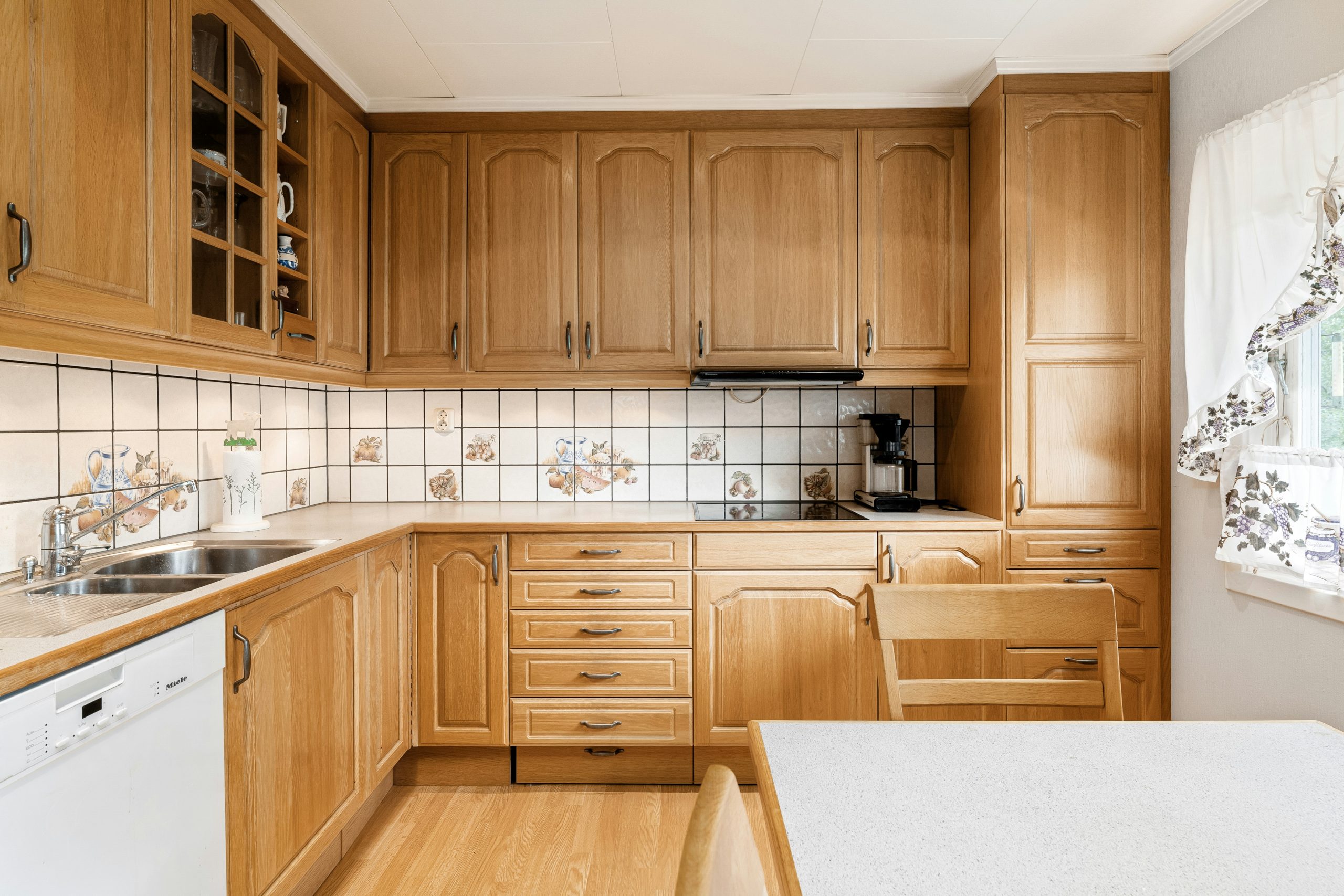 A kitchen with wooden cabinets and white counter tops