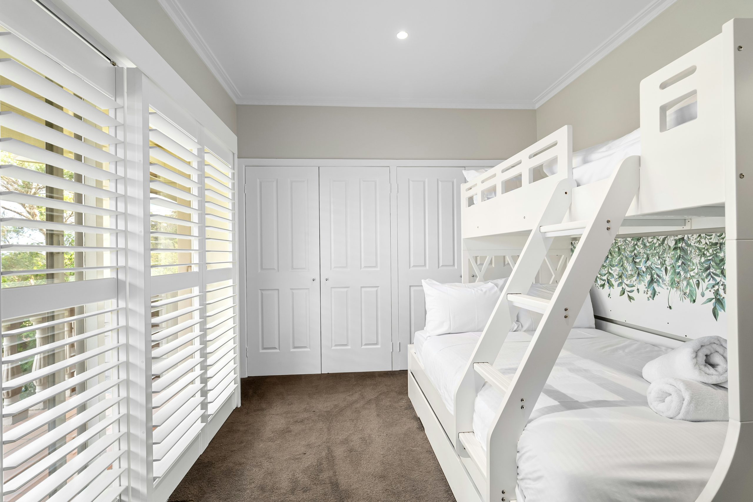 A room with bunk beds and white shutters