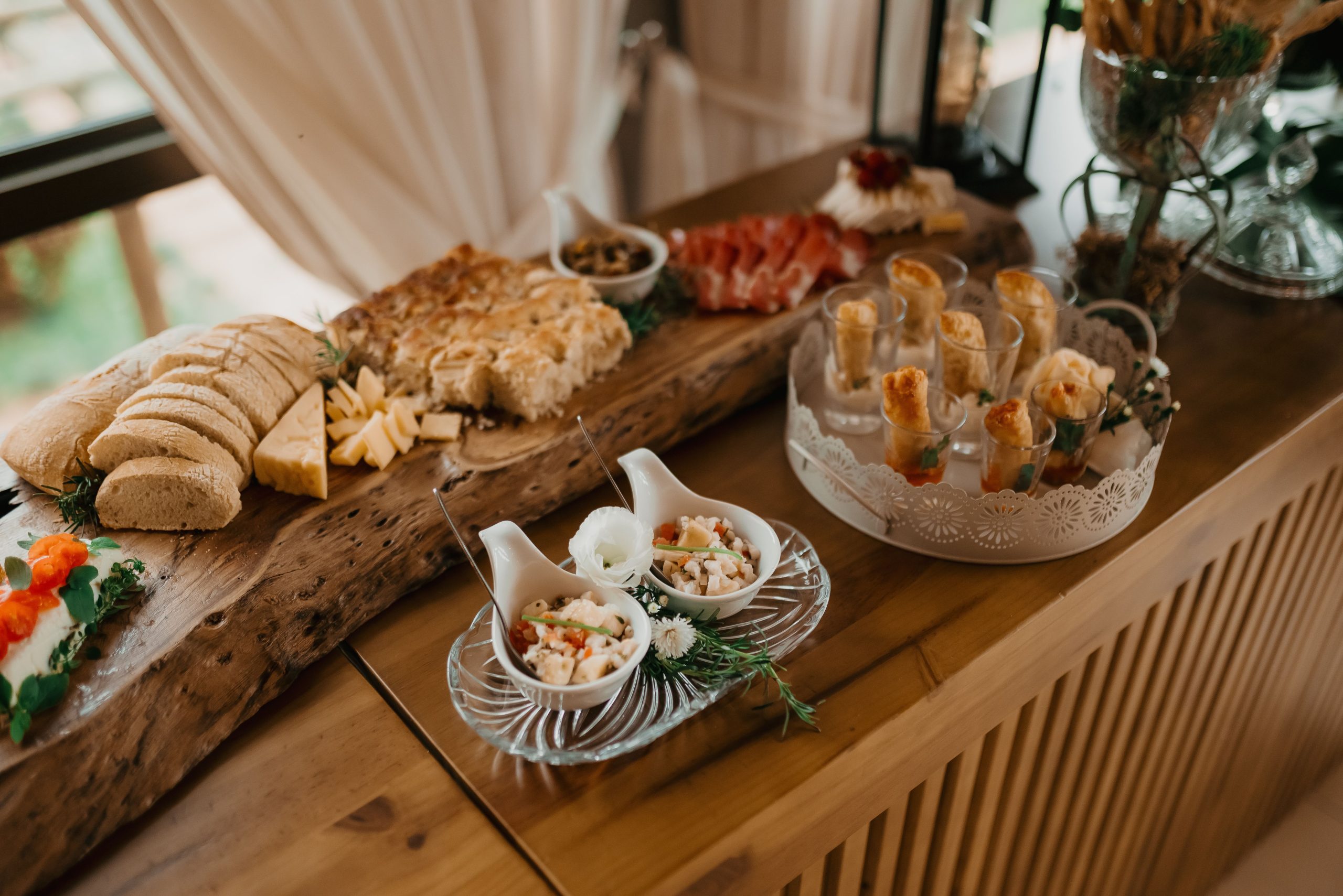 A rustic buffet setting with a variety of appetizers including bread, cheese, meats, and salads.