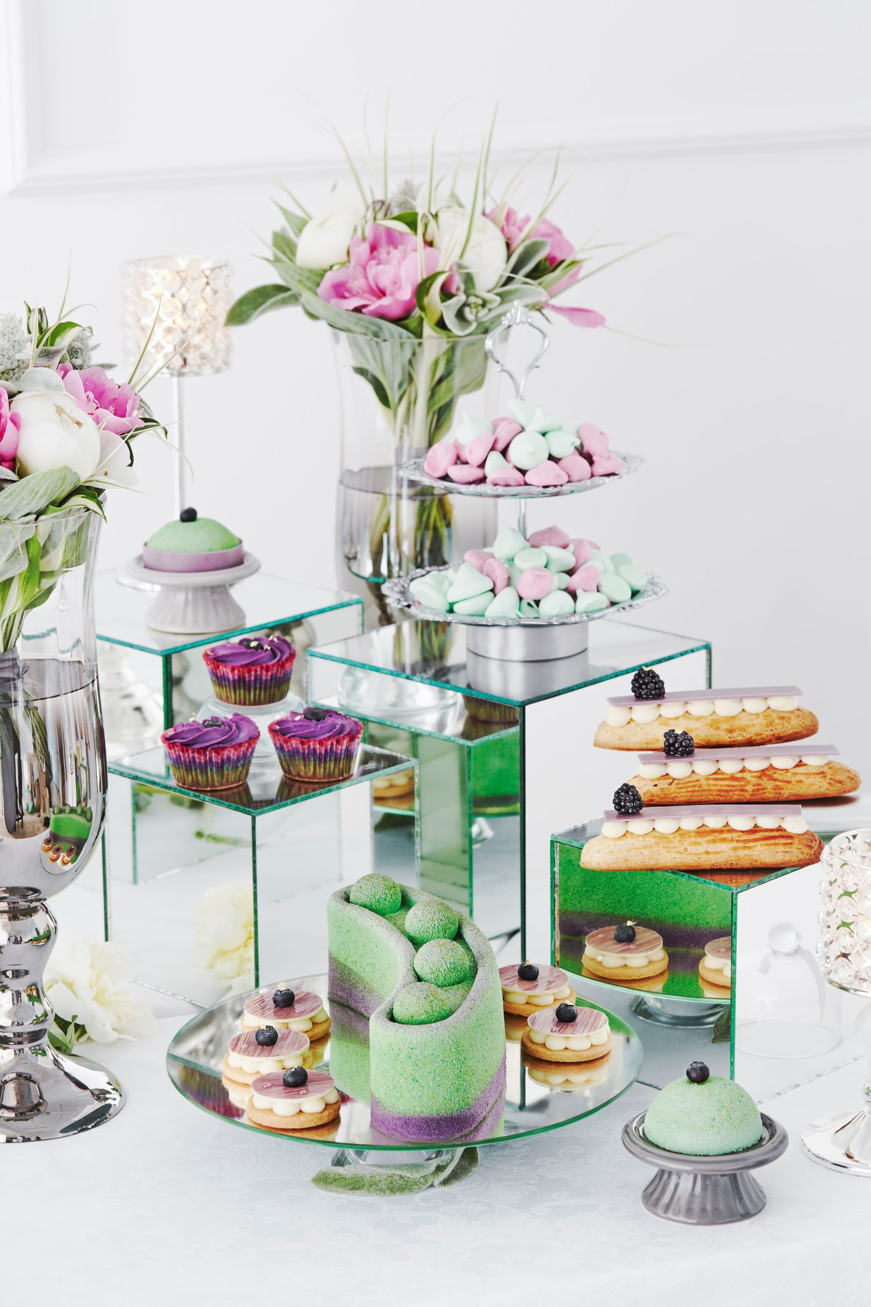 A stylish dessert arrangement featuring cupcakes, eclairs, and meringues with floral decor.