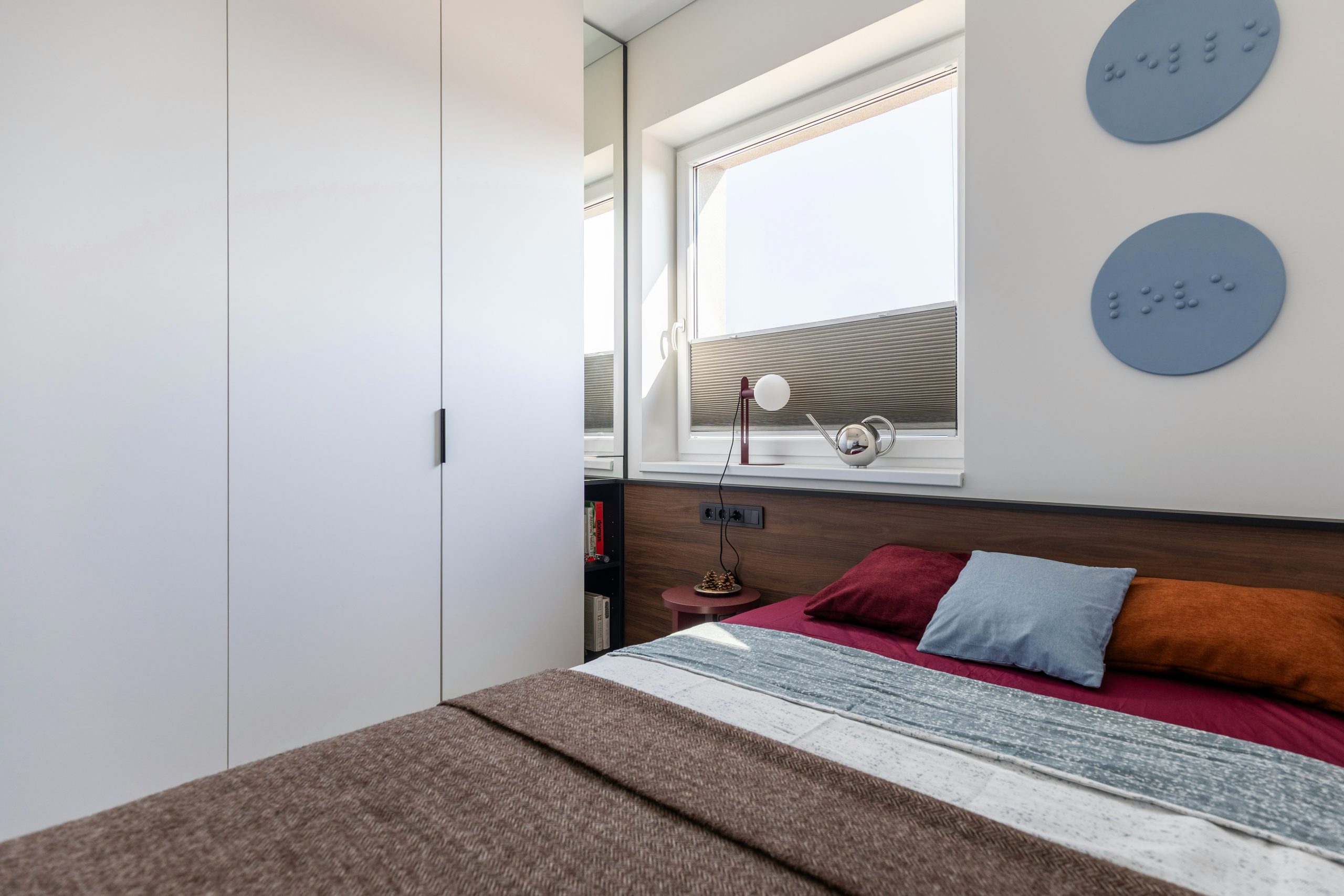 Accent colors—primarily deep red and rust—are introduced through furniture and textiles, adding visual contrast without disrupting the overall balance.