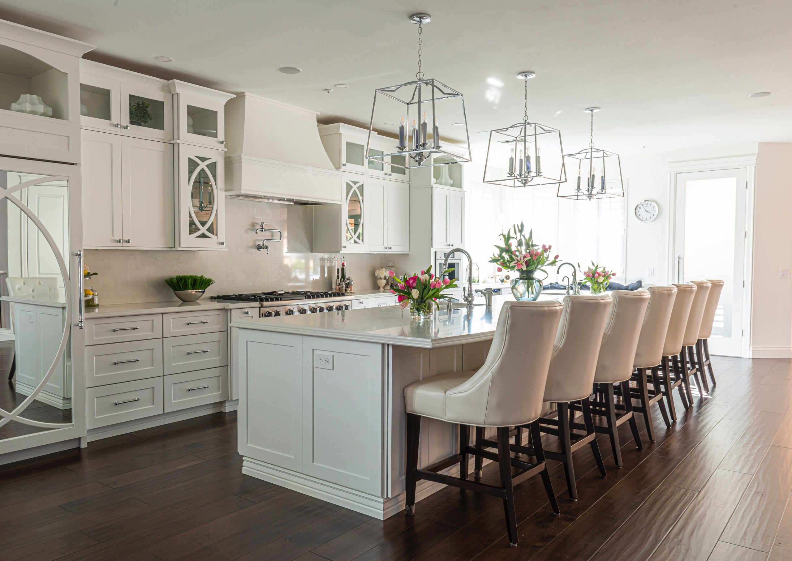 Beautiful modern kitchen interior featuring white cabinets, island, and elegant bar stools.