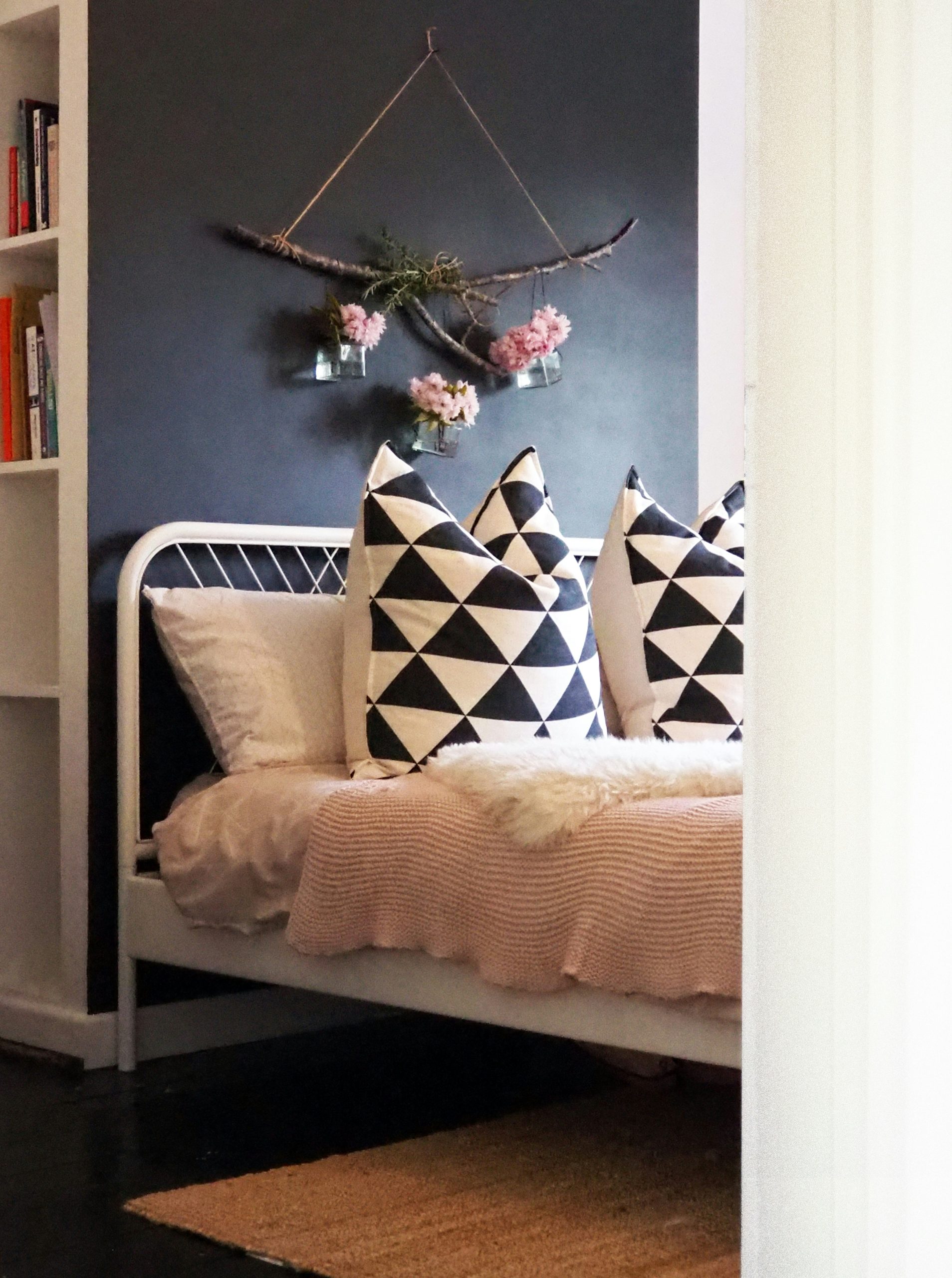 Bedroom with a black feature wall with blossom and rosemary floral display