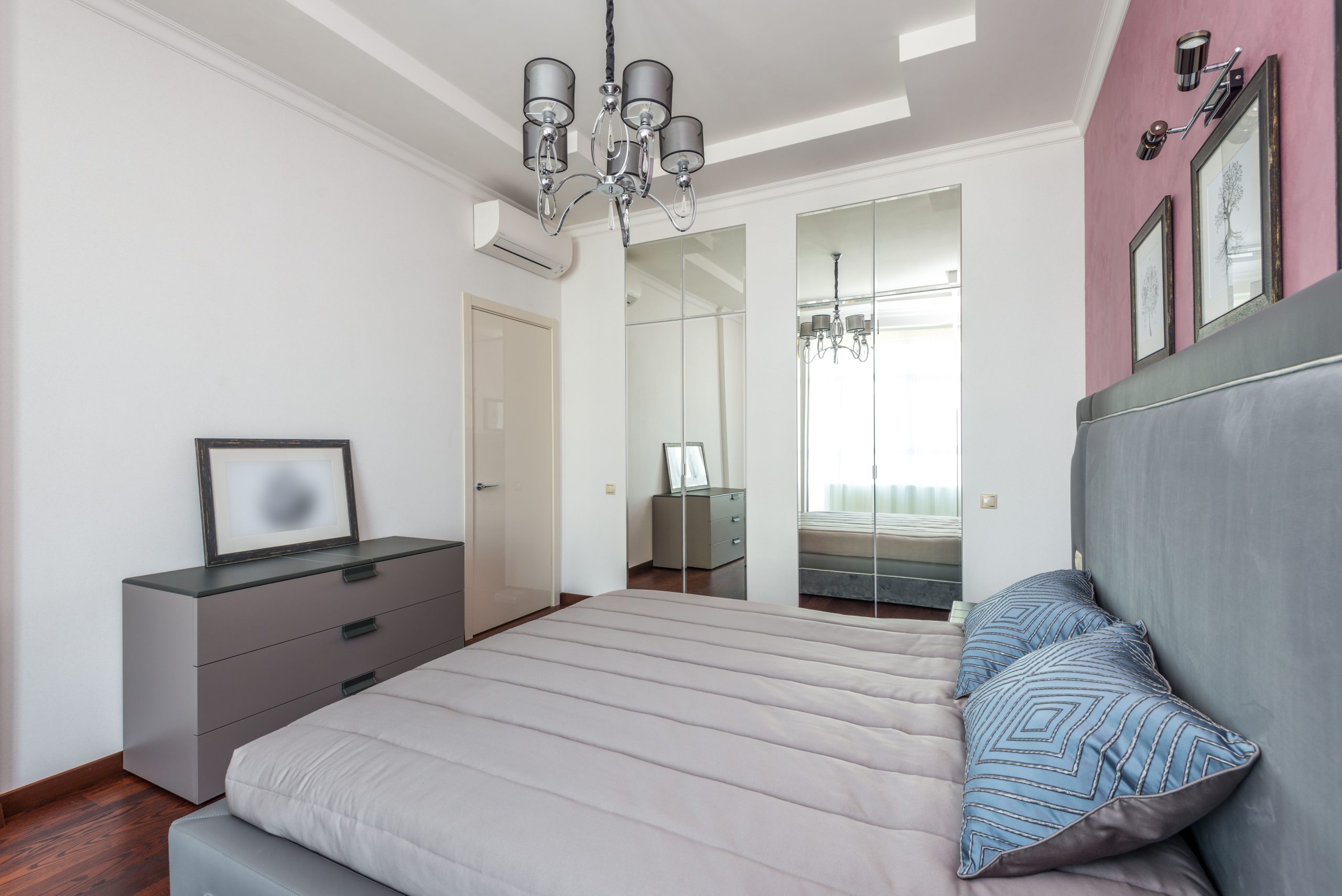 Bright contemporary bedroom featuring stylish decor and mirrored closet.