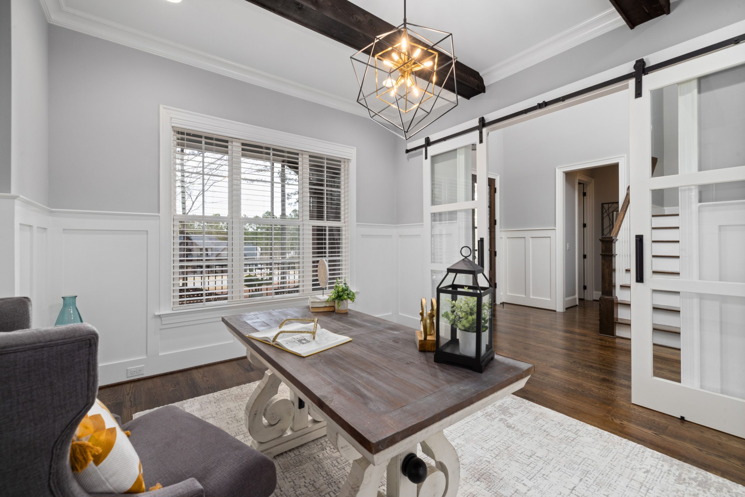 Bright living room with modern decor, featuring a wooden table, lantern, and sliding barn doors.