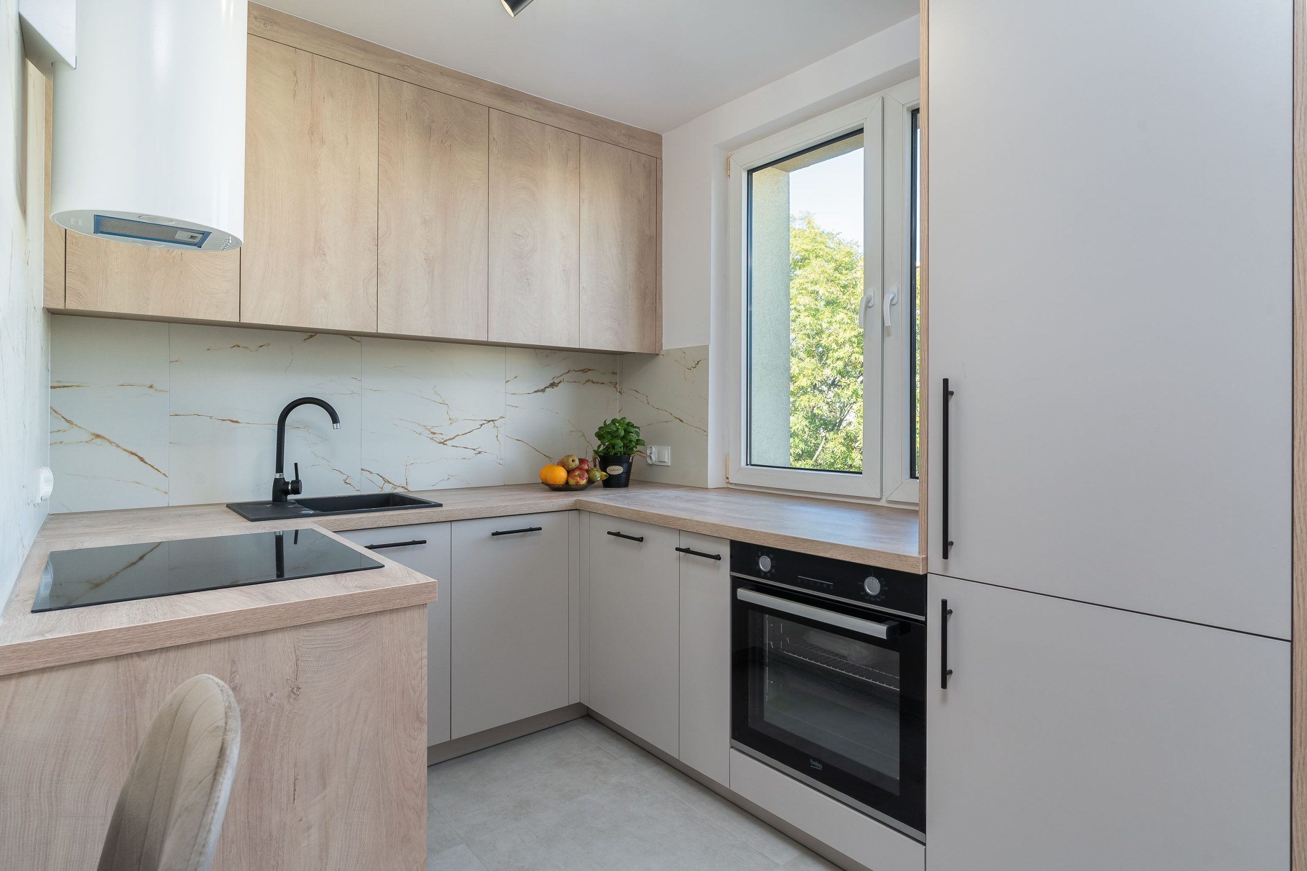 Bright minimalist kitchen with light wood cabinetry and modern appliances.