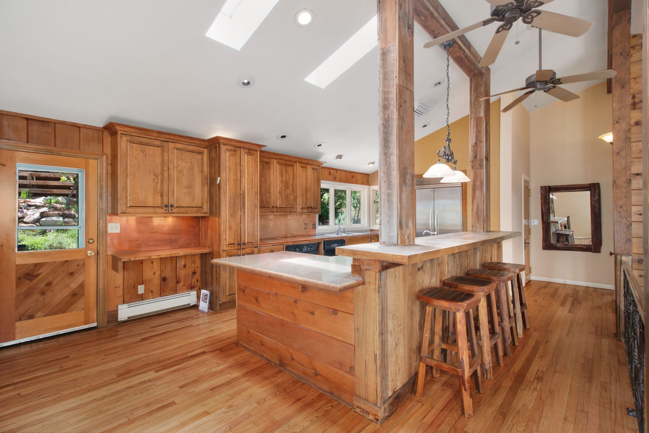 Bright rustic kitchen featuring wood elements, skylights, and a breakfast bar with stools.