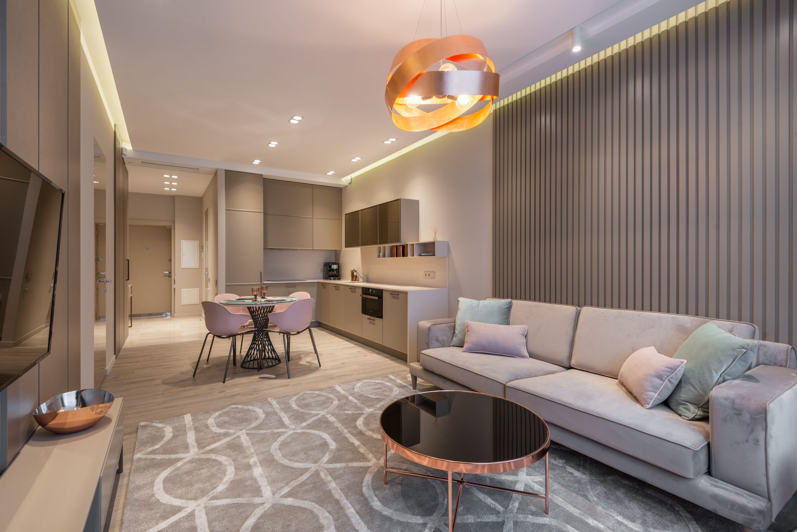 Comfortable couch and round coffee table near kitchen zone decorated with creative chandelier in contemporary flat