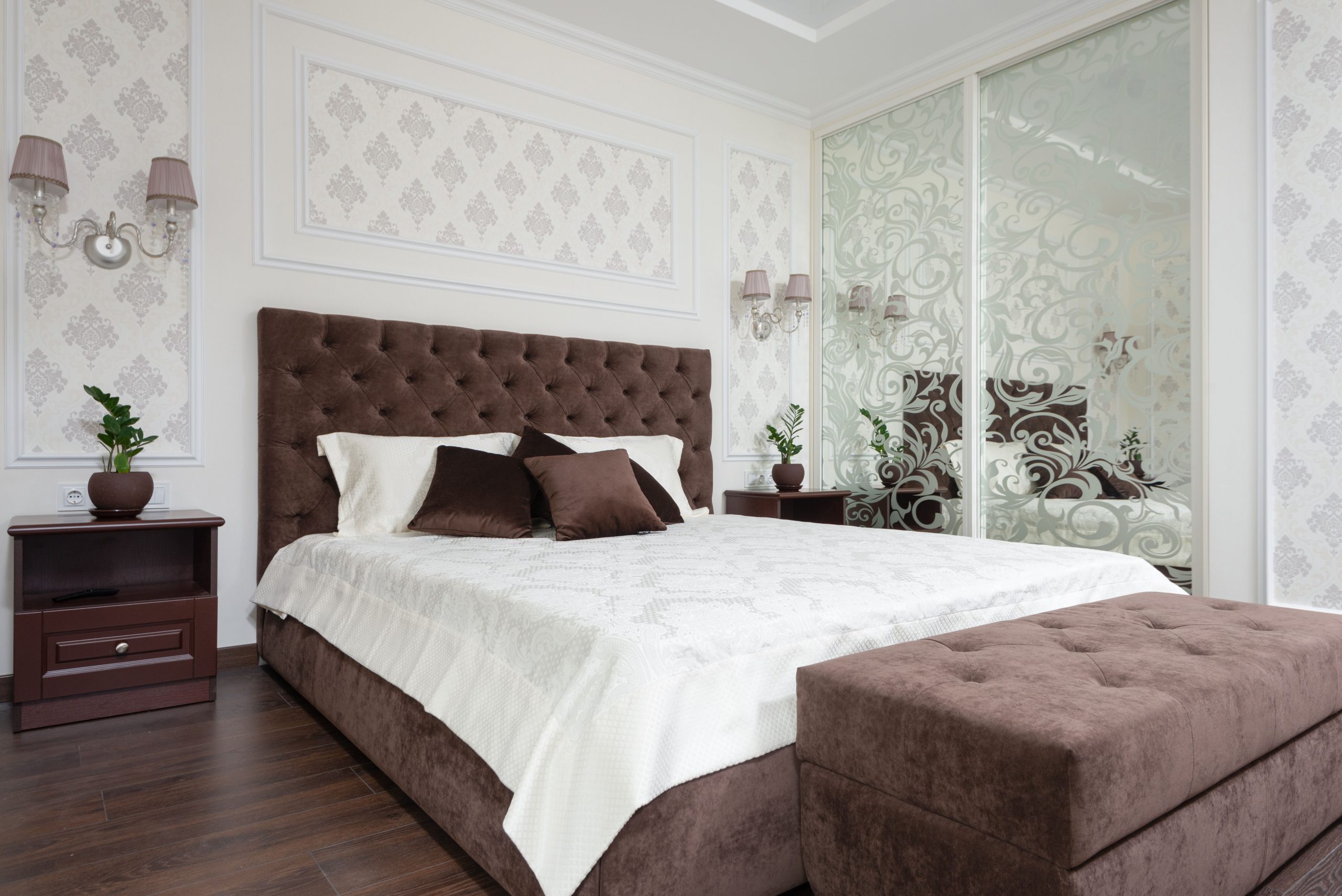 Luxurious bedroom interior with brown tufted headboard and plush ottoman.