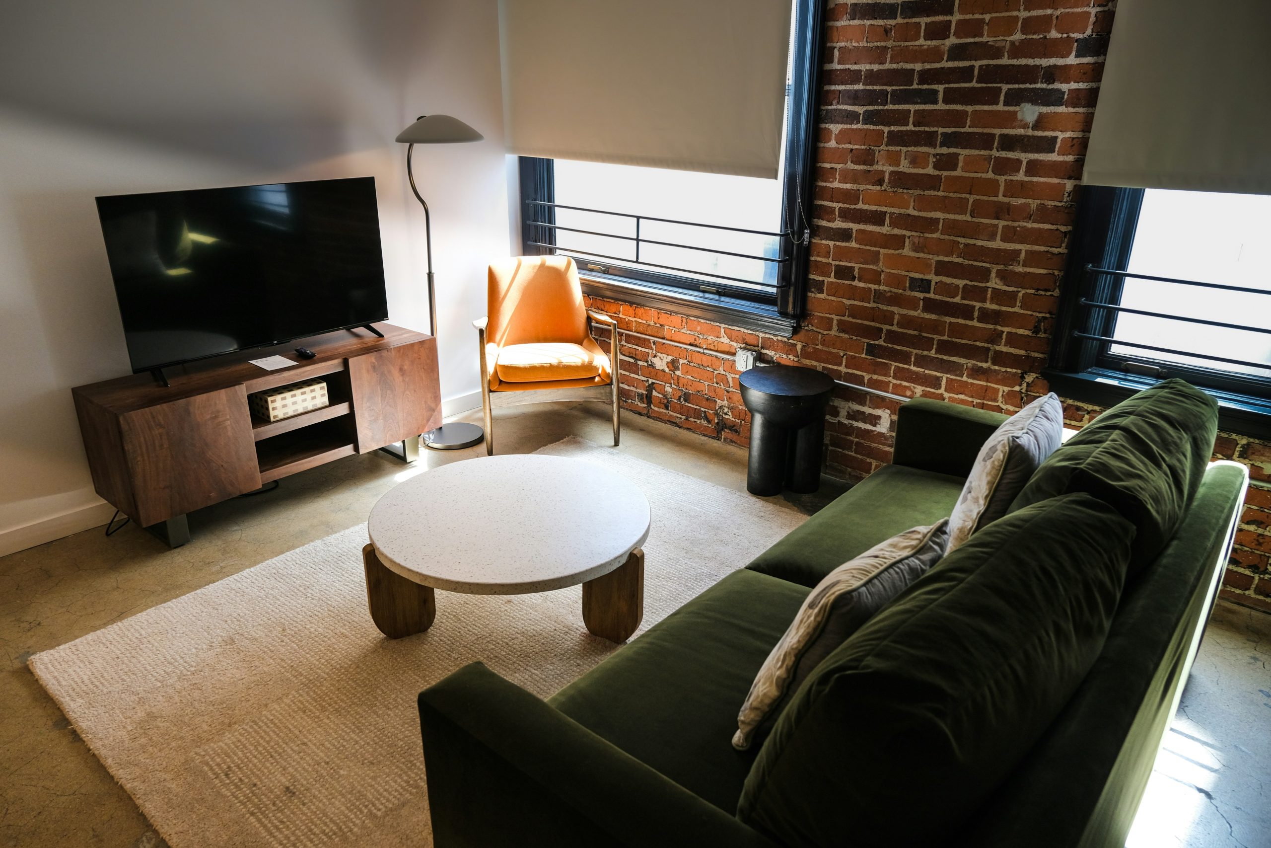 Modern living room with green sofa and brick wall.