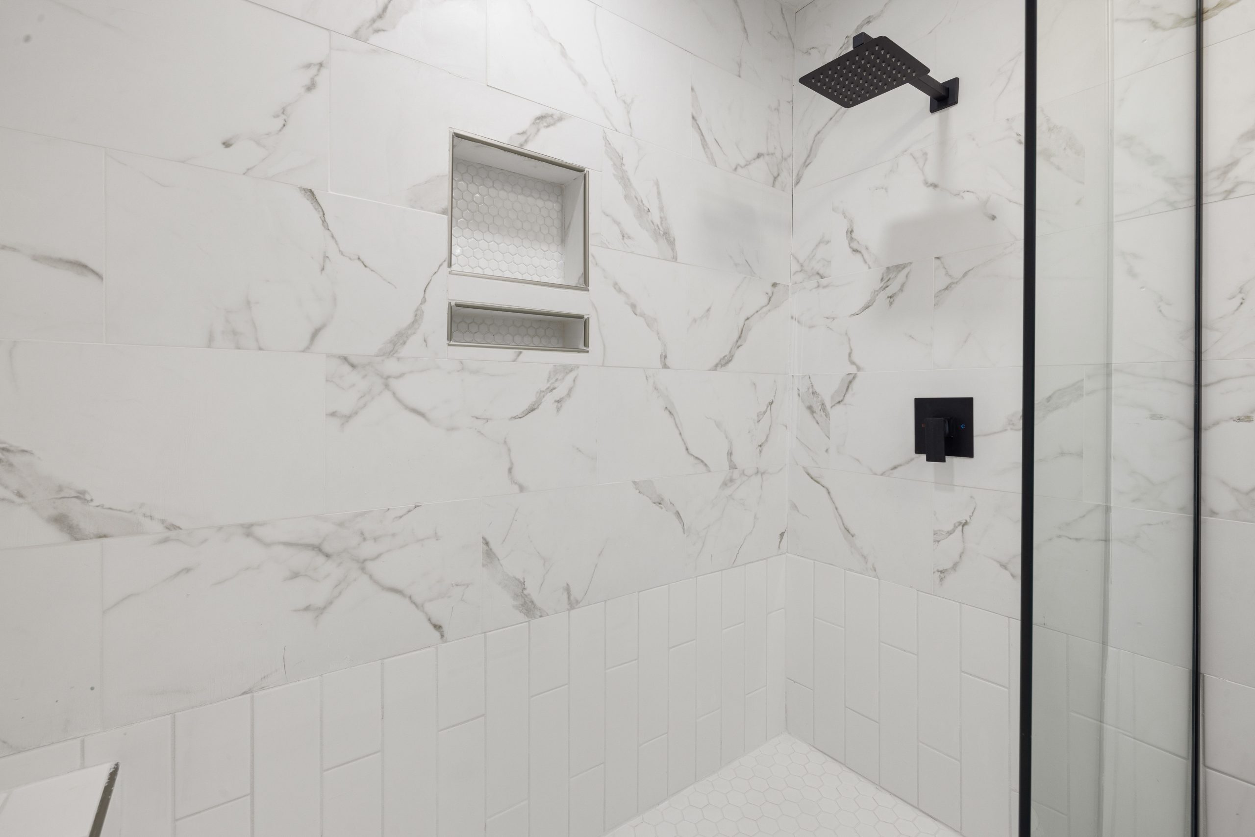 Sleek bathroom shower featuring marble tiles and black fixtures, perfect for modern luxury home design.